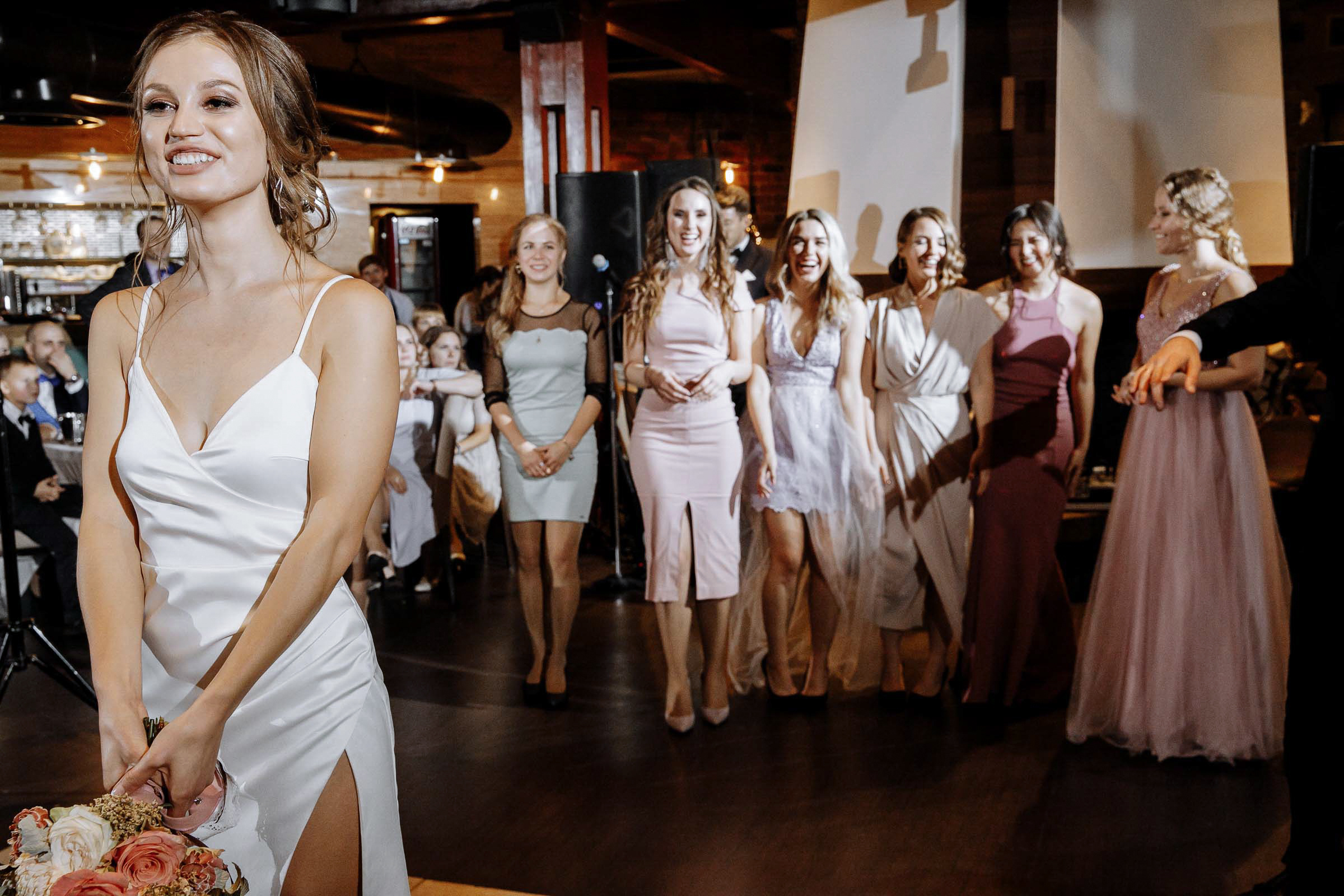Bride tossing bouquet in venue, by Tanya Bodgan, London wedding photographer.  