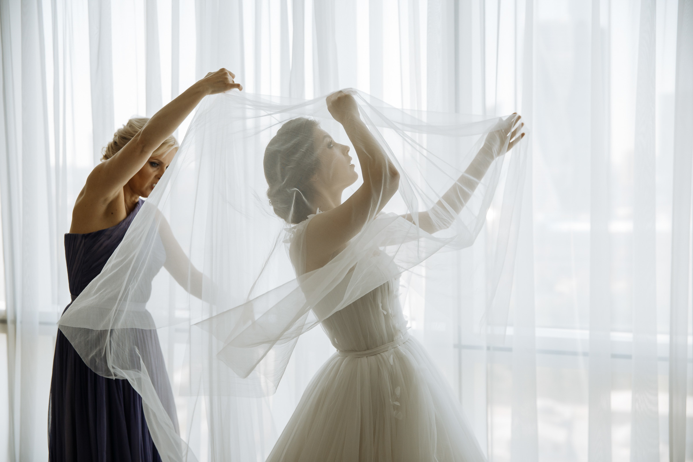 Bride fixing veil indoors, by Tanya Bogdan, Exeter wedding photographer.  