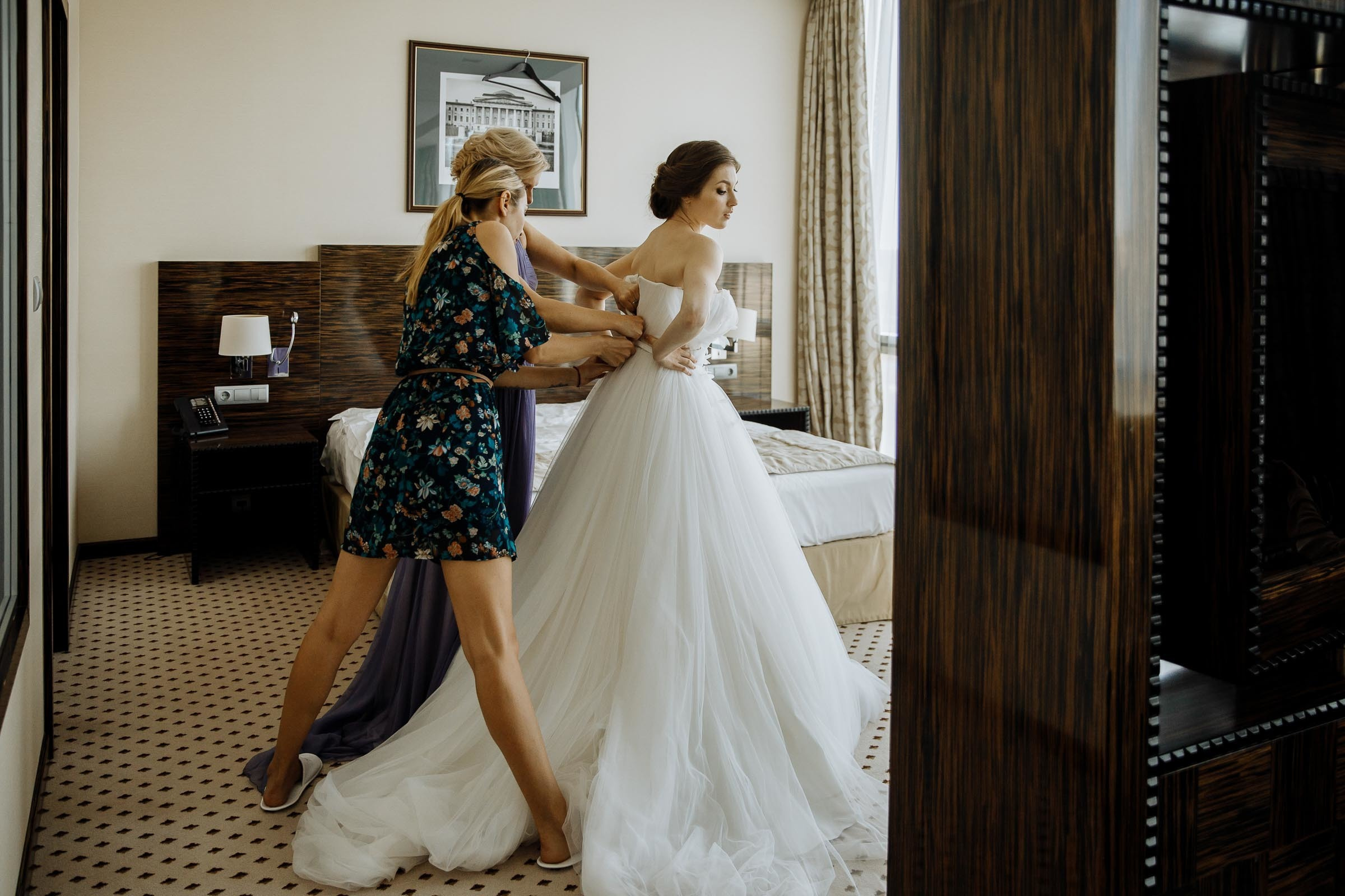Adjusting dress in suite, by Tanya Bogdan, Bude, Cornwall wedding photographer.  
