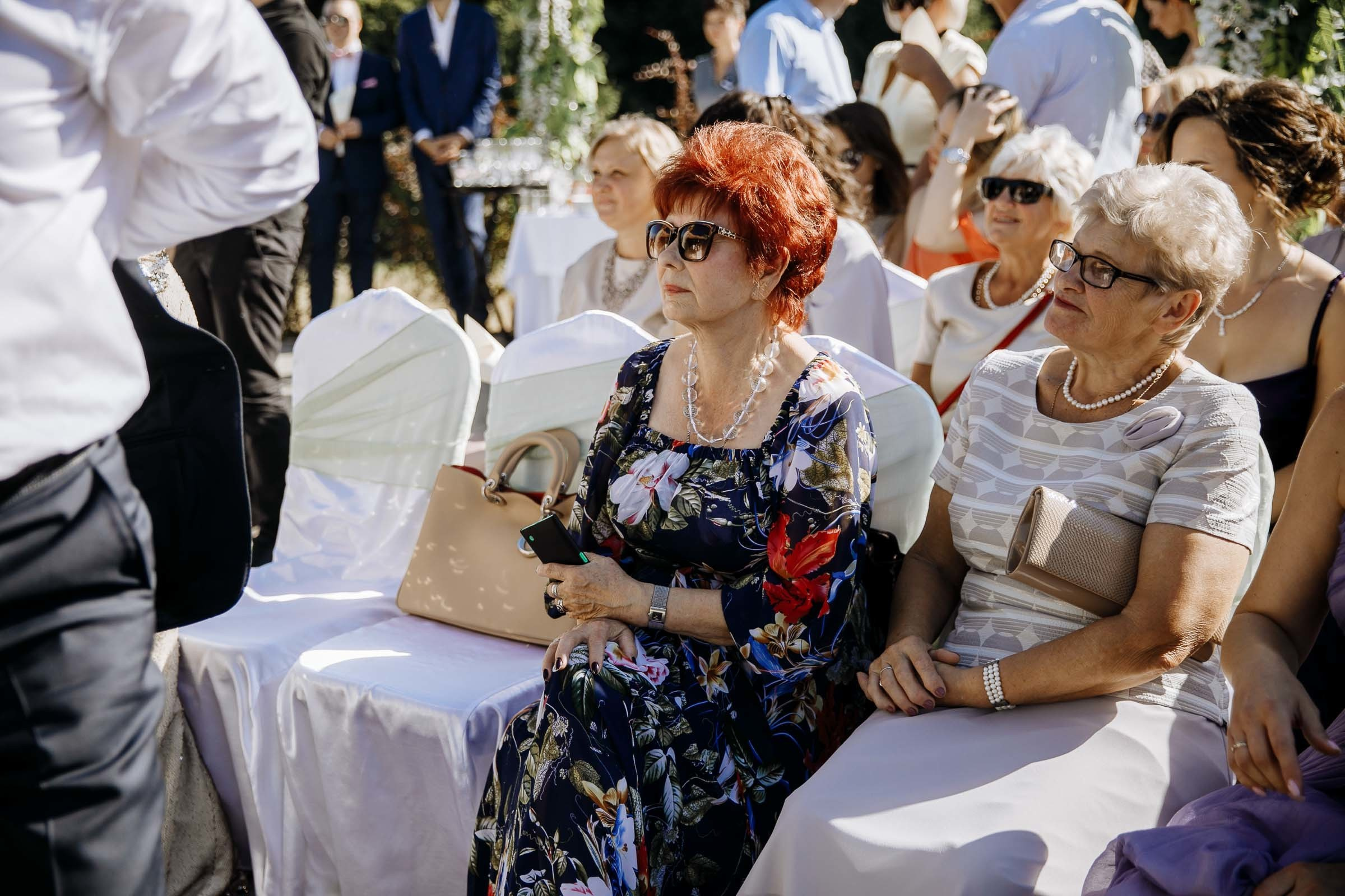 Guests smiling during ceremony in garden, by Tanya Bogdan, Bude reportage wedding photographer.  