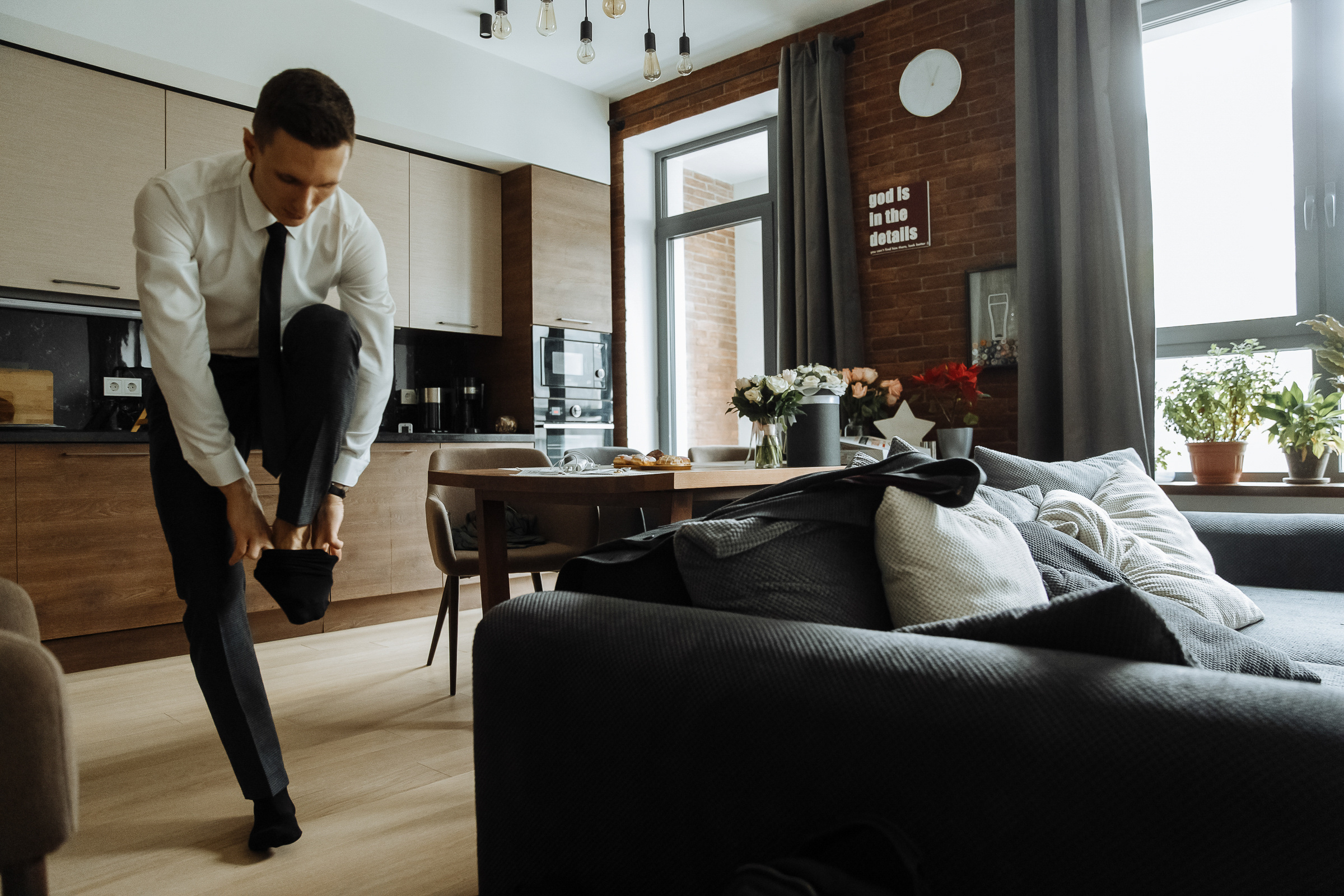 Groom putting on shoes in morning light, by Tanya Bogdan, Bude, Cornwall wedding photography.  