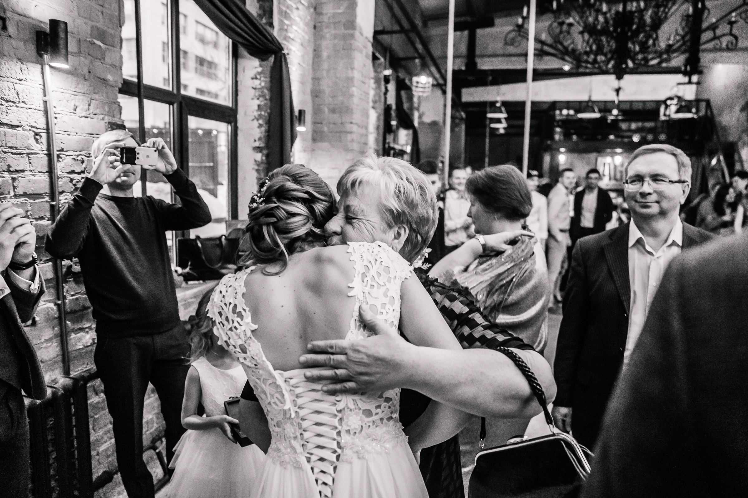 Guests congratulating bride in black and white, by Tanya Bogdan, Bude, Cornwall wedding photographer.  
