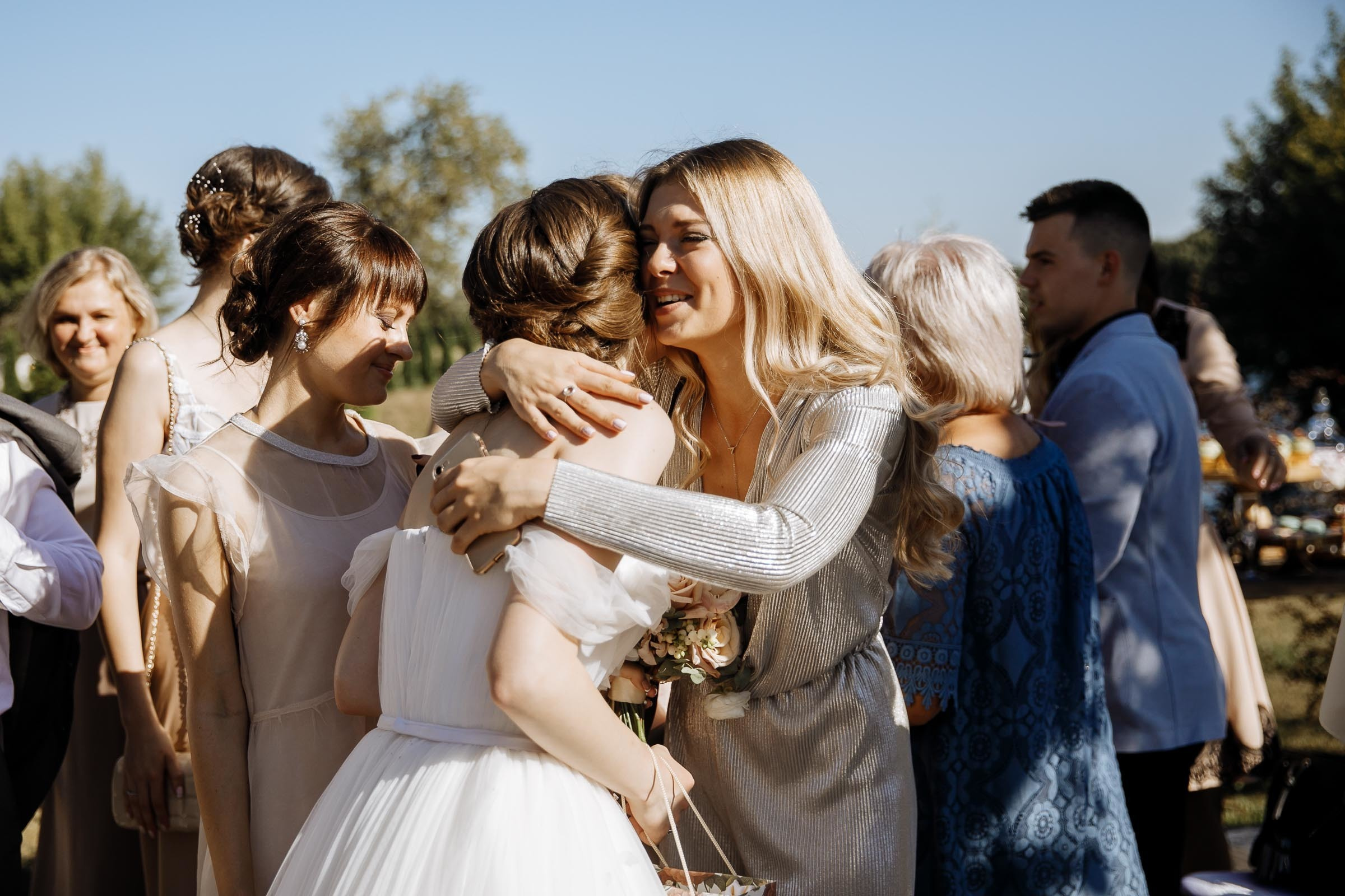 Guests hugging bride after ceremony in garden, by Tanya Bogdan, Cornwall reportage wedding photographer.  