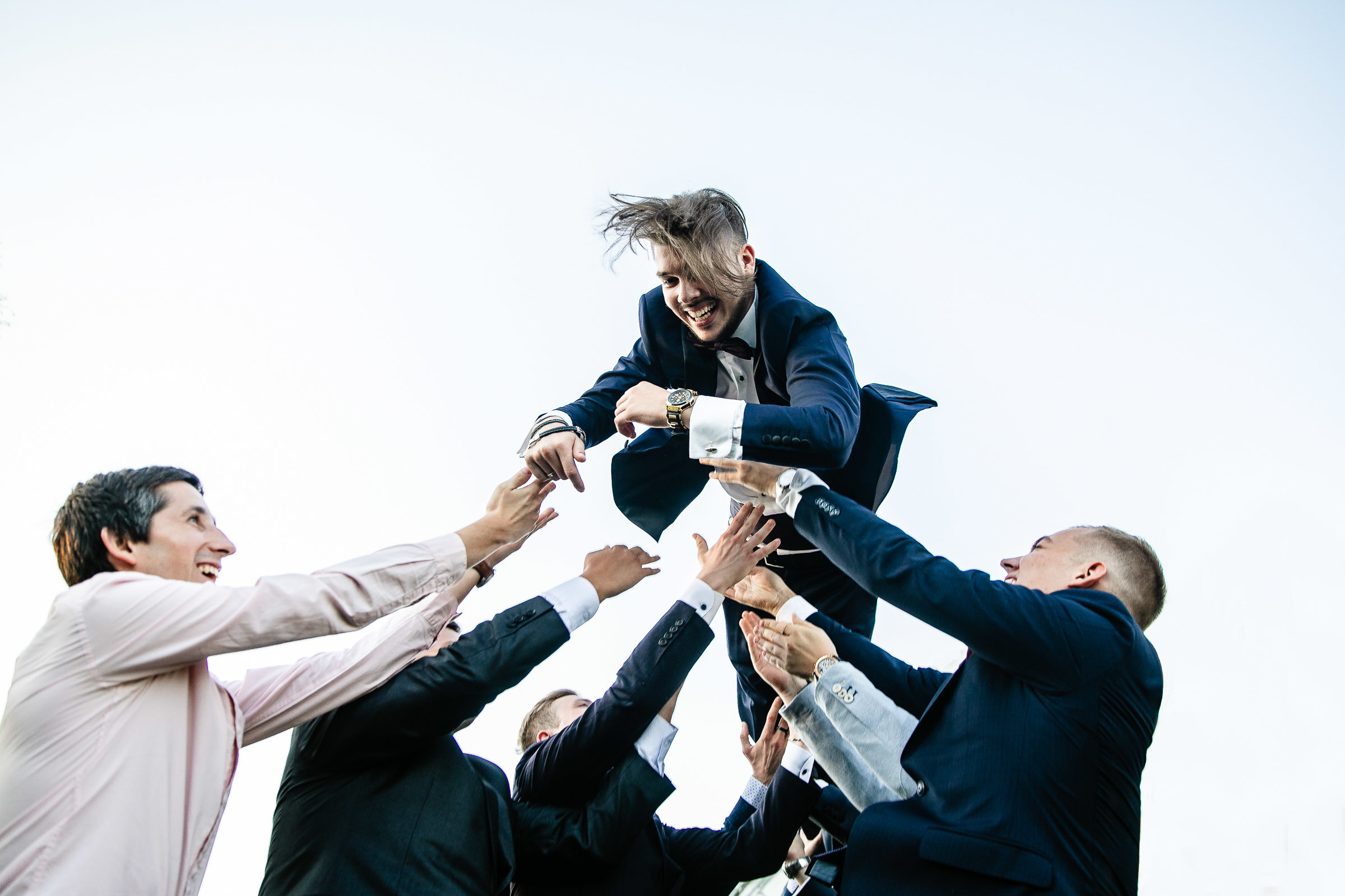 Groomsmen throwing groom in garden venue, by Tanya Bogdan, Bude wedding photography.  