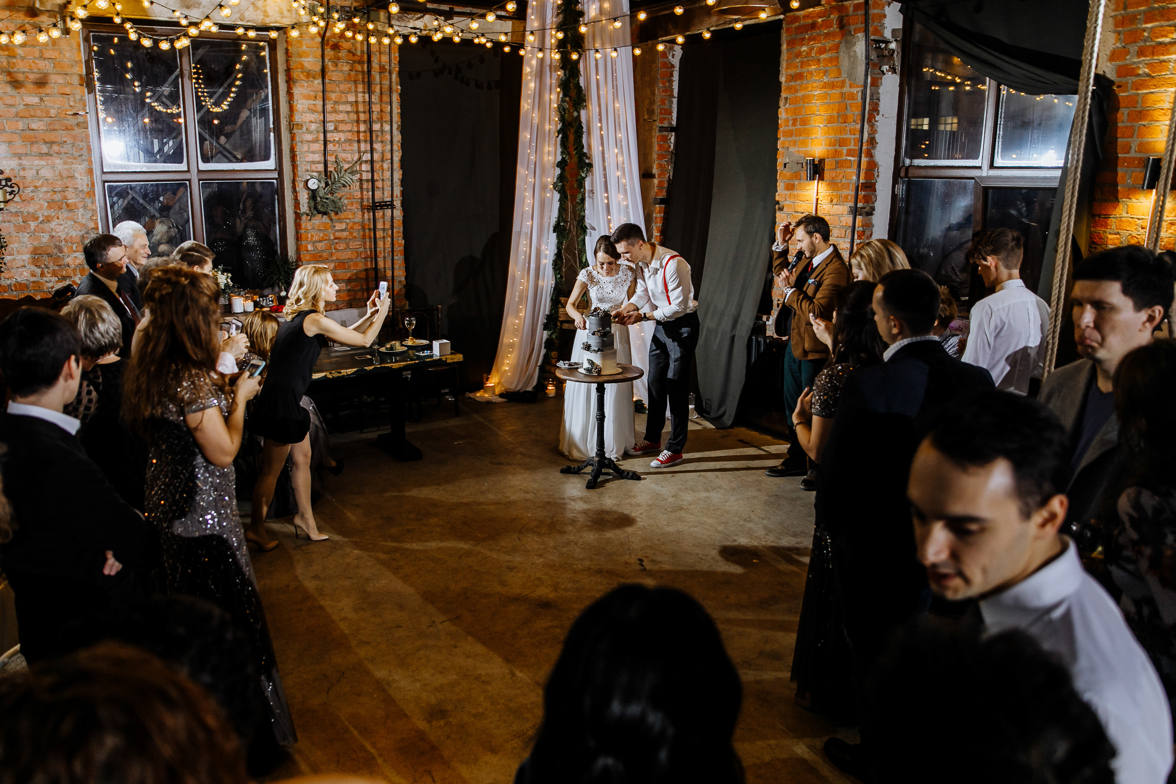 Guests cheering at cake cutting, by Tanya Bogdan, Bude, Cornwall wedding photographer.  
