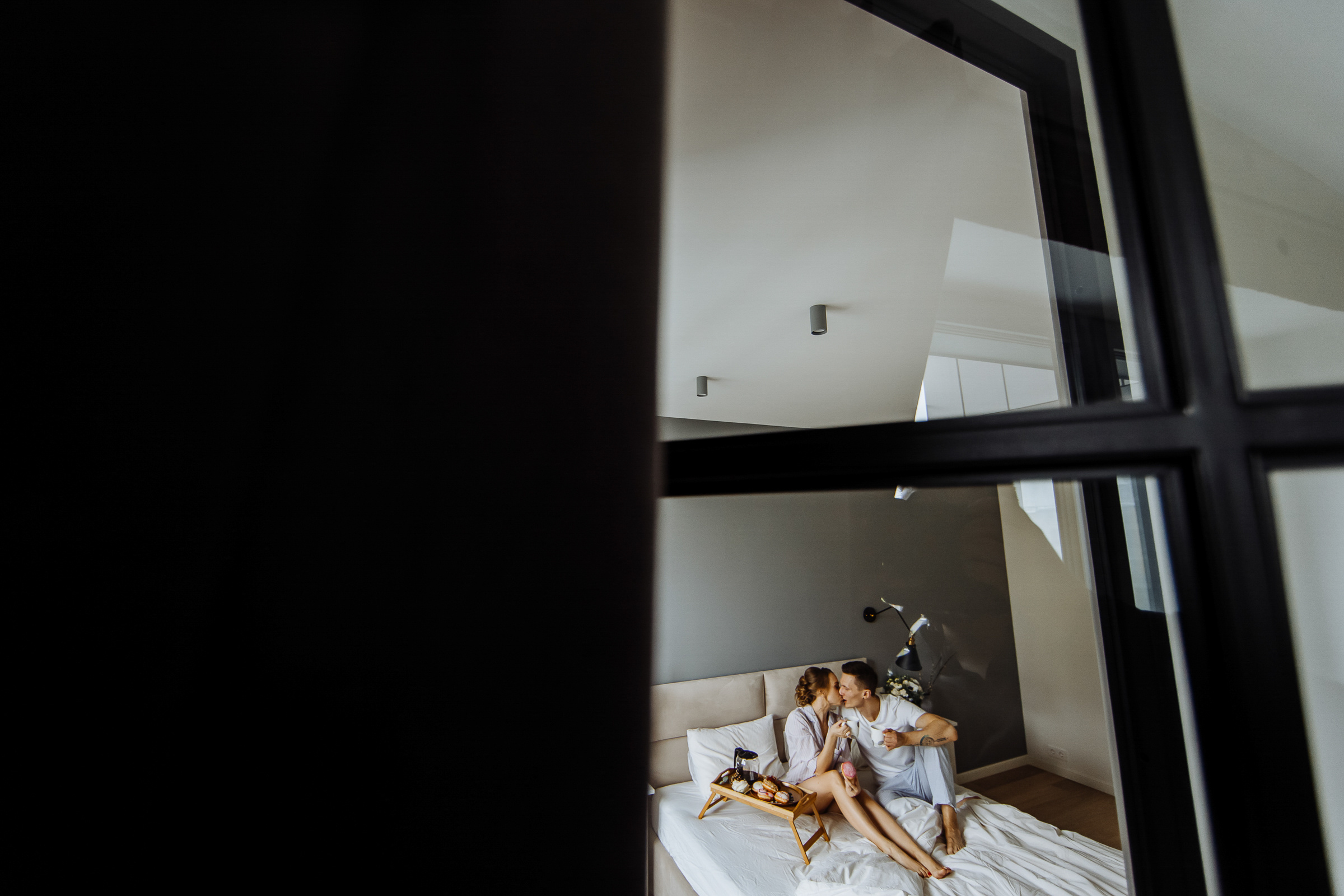 Bride and groom sitting on bed, by Tanya Bogdan, Bude, Cornwall wedding photographer.  