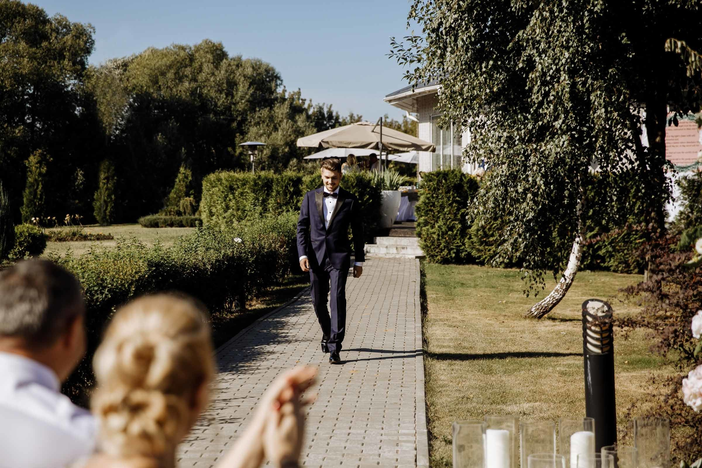 Groom walking down aisle in garden, by Tanya Bogdan, Bude, Cornwall wedding photographer.  