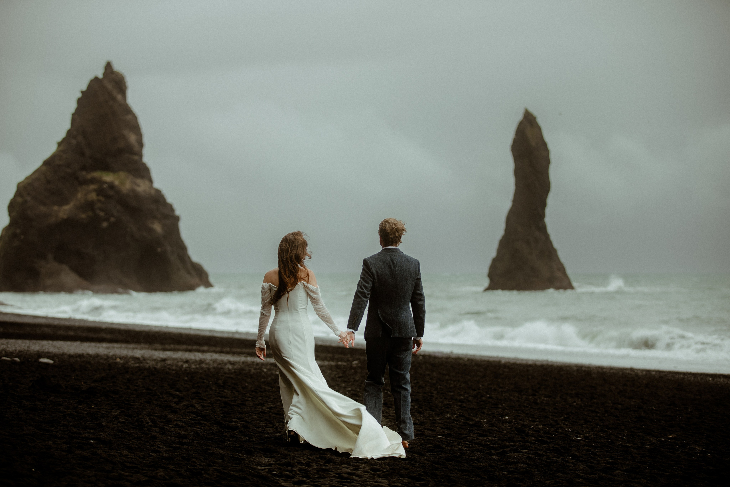 A couple walking on the beach with black sand