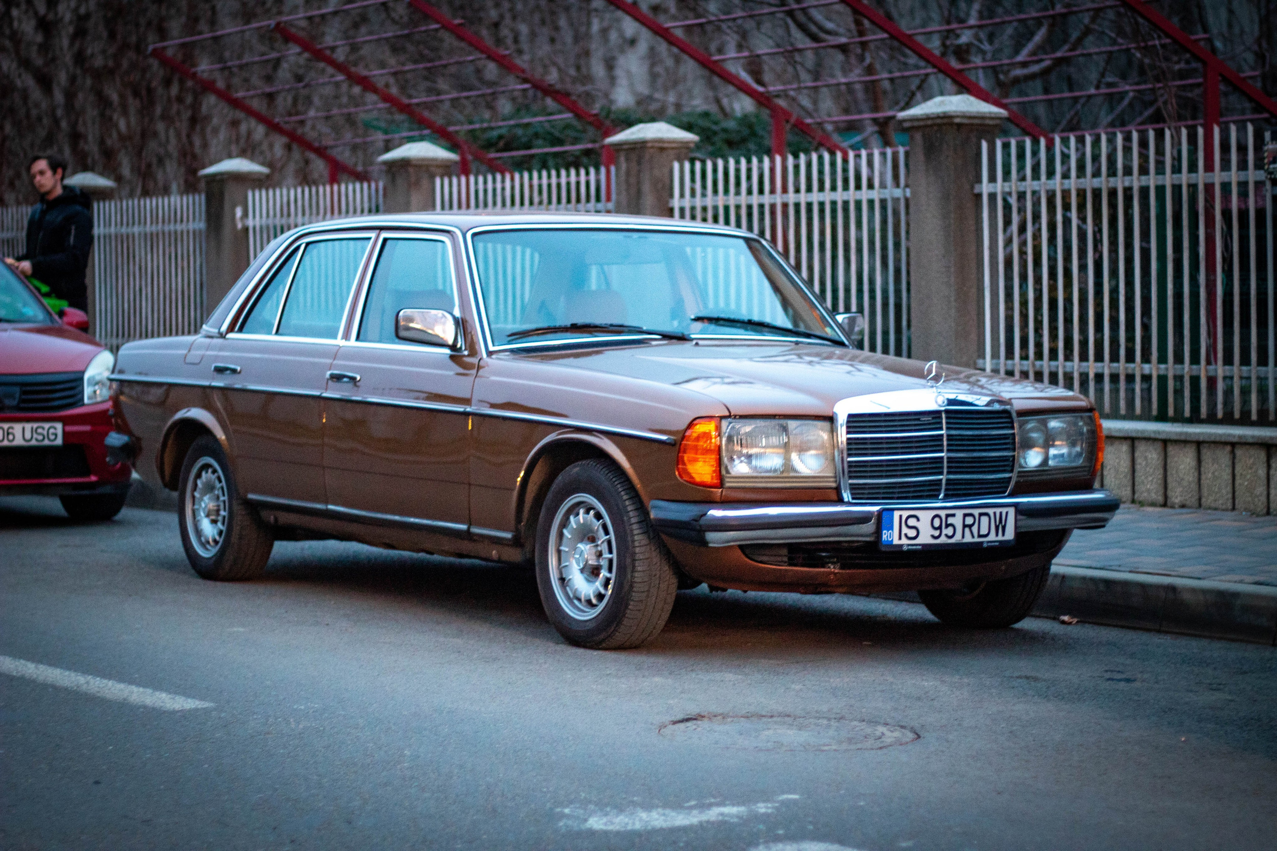 Vintage car reflecting street lights on wet pavement in a nighttime city scene.