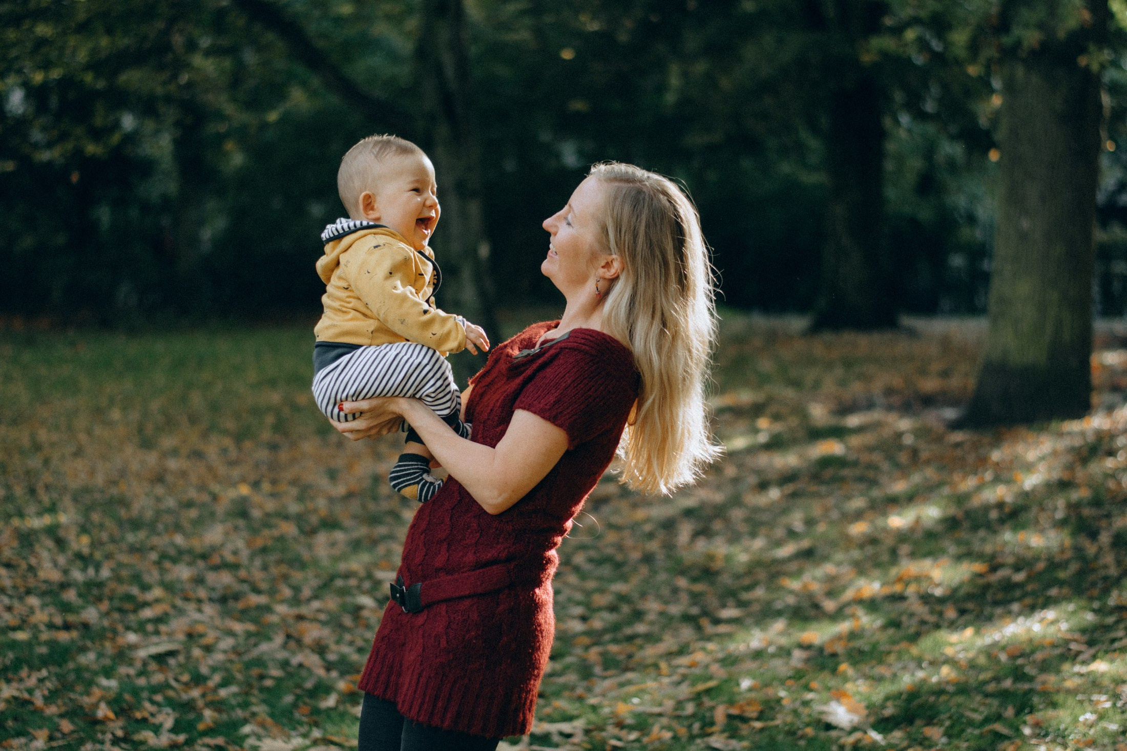Фотосессия матери с ребёнком — мама держит малыша на руках в осеннем парке