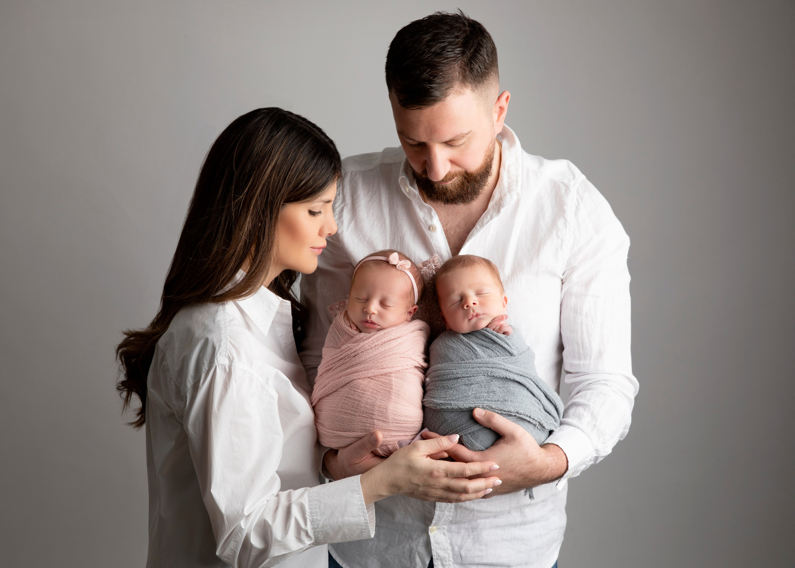 "En varm och kärleksfull familjefotografi med nyfödda tvillingar och deras äldre bror eller syster. Bilden fångar glädjen och stoltheten i att vara en del av en utökad familj."