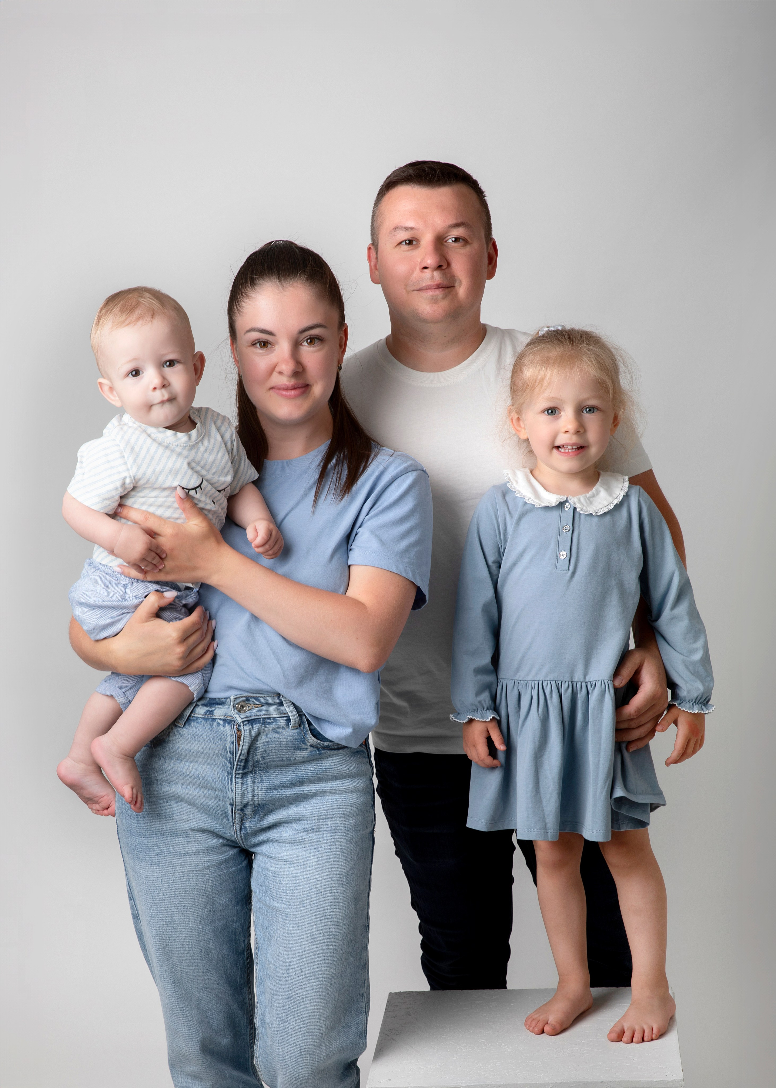 Familjefotografering i studion fångar ögonblicket av lycka med barn, mamma och pappa tillsammans.