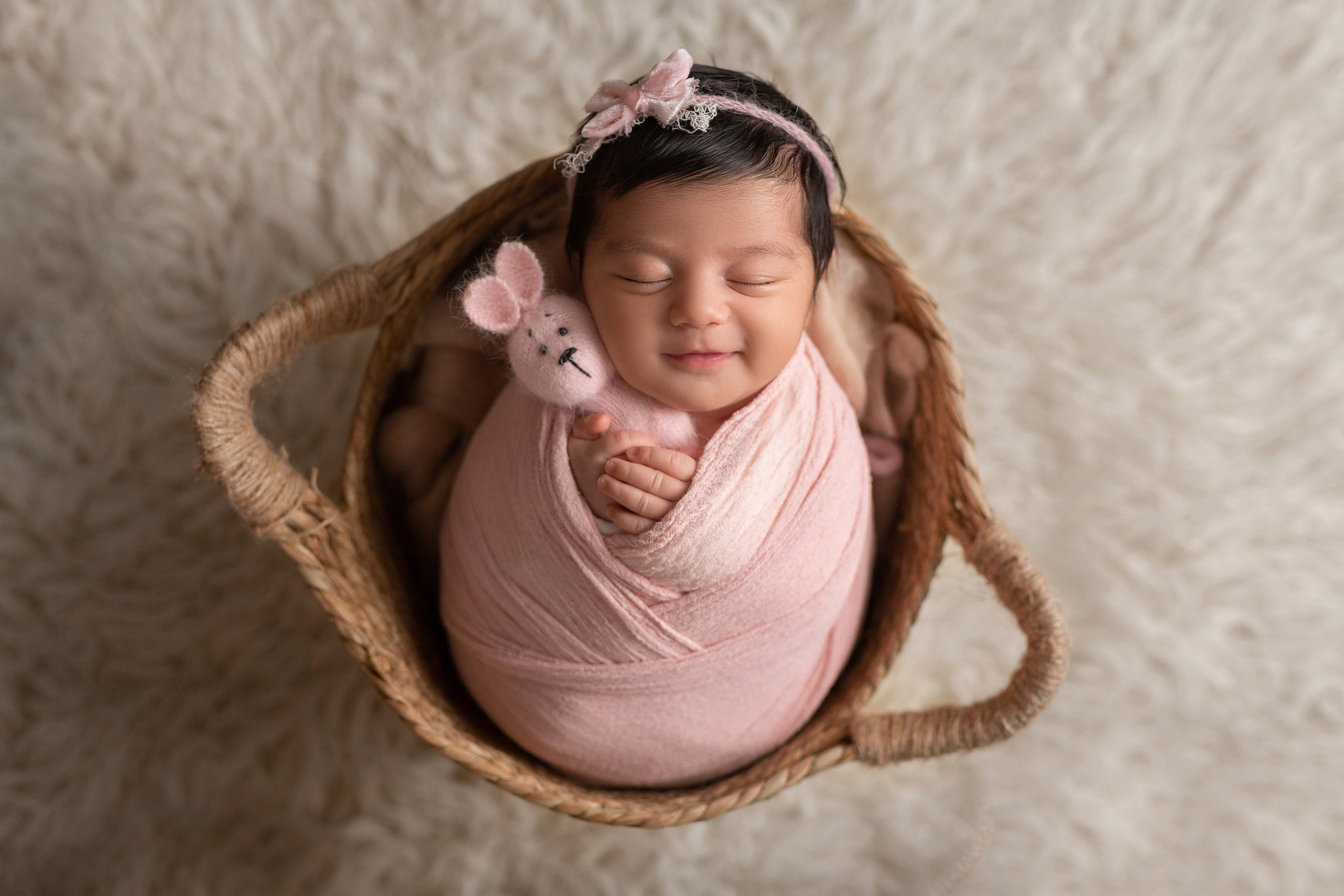 Frisch geborenes Baby eingewickelt in eine Decke, liegt in einem rustikalen Körbchen – Newbornfotografie in Iserlohn