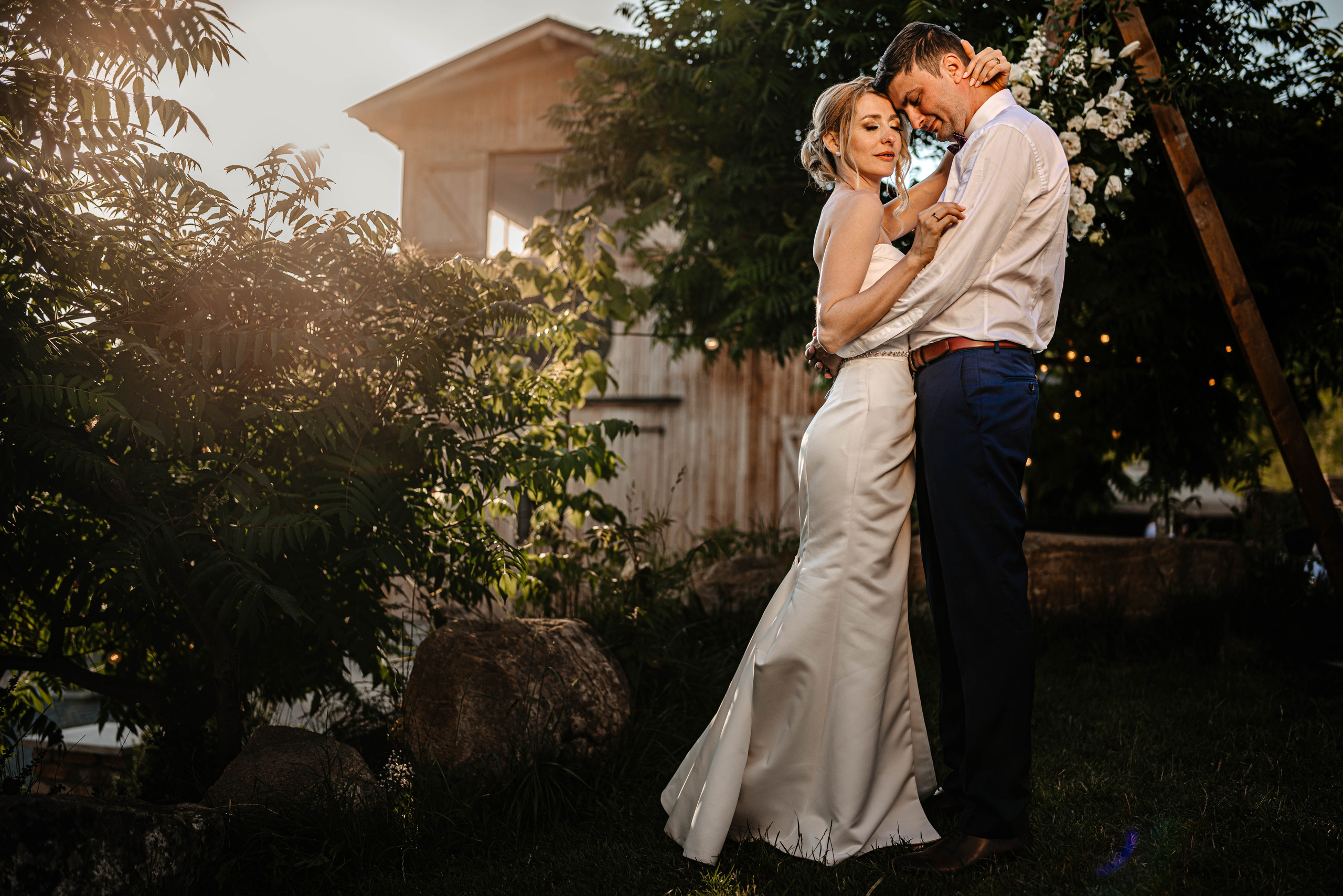 Radu Rahovan Fotograf de nuntă Cluj – mire și mireasă îmbrățișați la apus, în fața unui barn rustic.