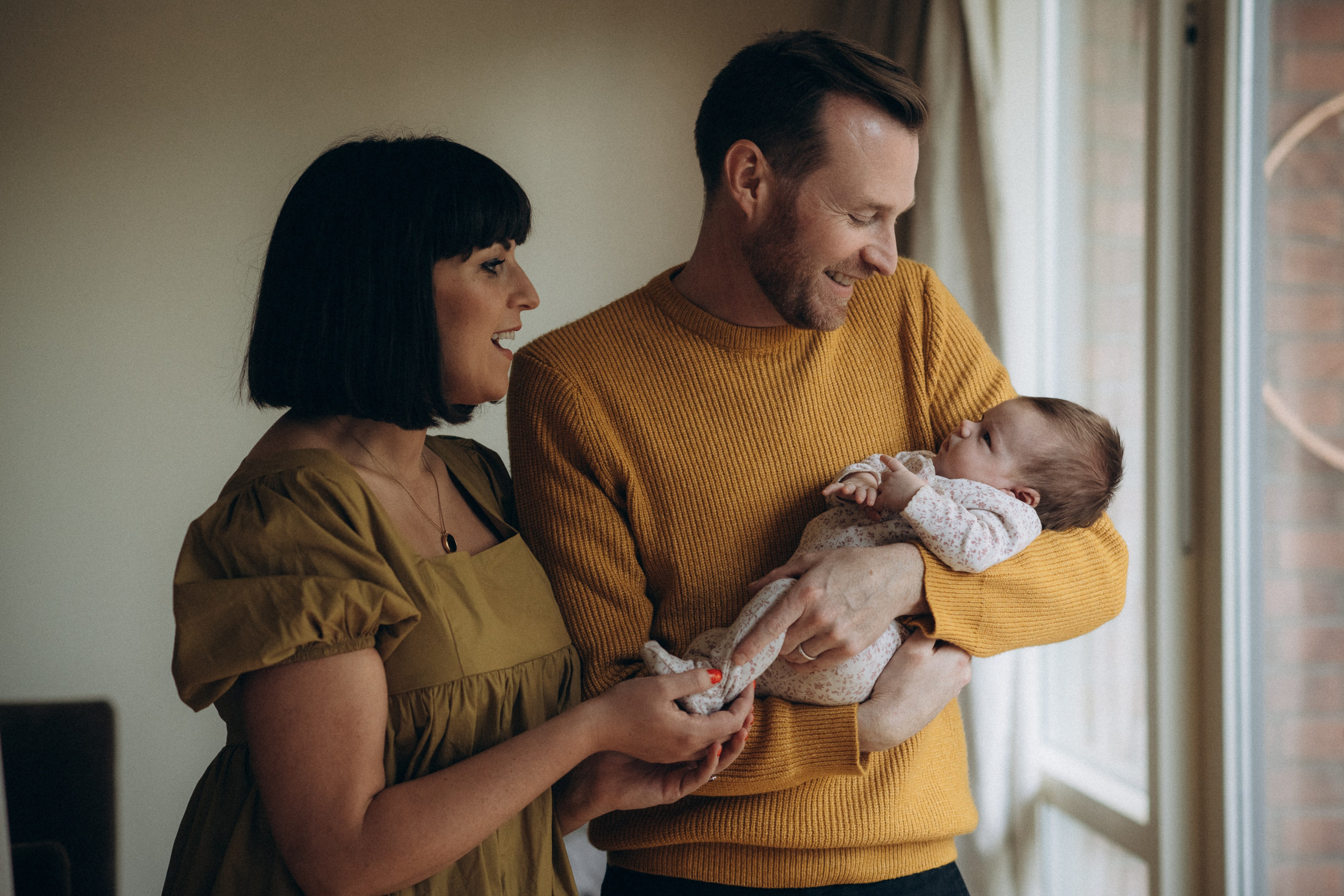 family with the baby standing by the window
