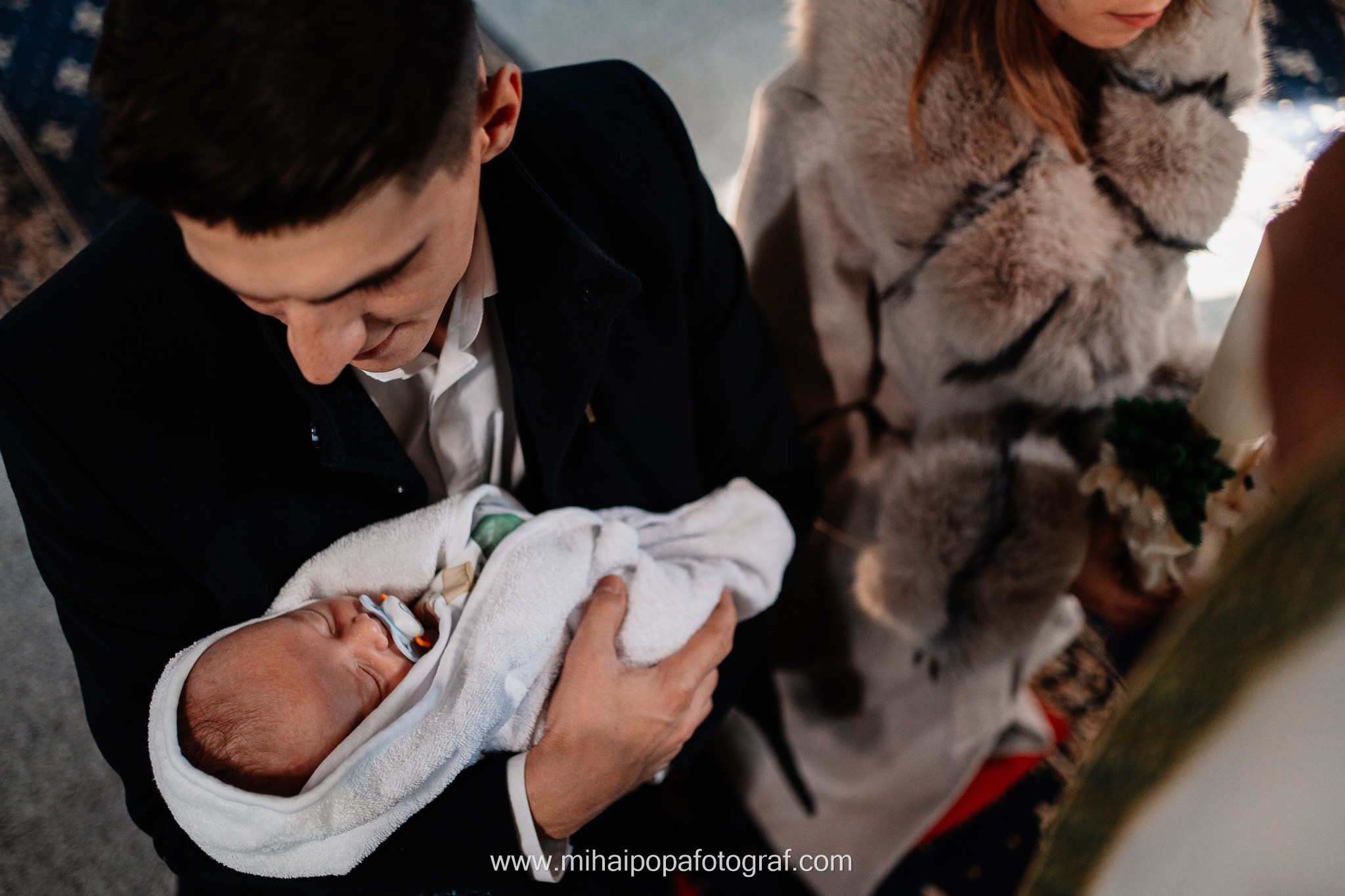 Instantaneu plin de tandrețe dintre părinți și bebeluș în ziua botezului, realizat în ilfov. Fotografie profesională de botez, capturând emoțiile autentice ale familiei într-un decor luminos și cald