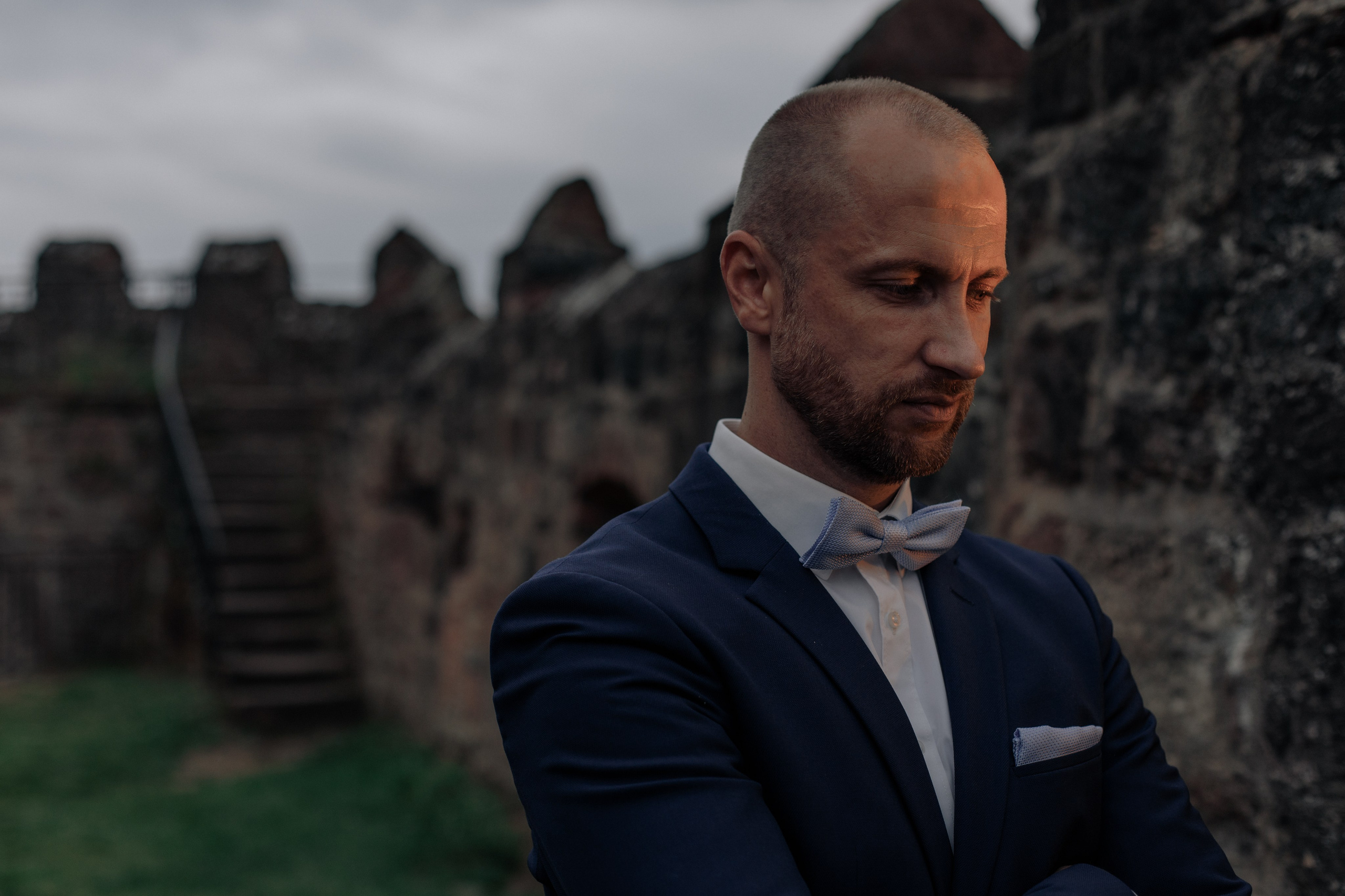 Der Bräutigam schaut nachdenklich an der Mauer der Burg Breuberg.