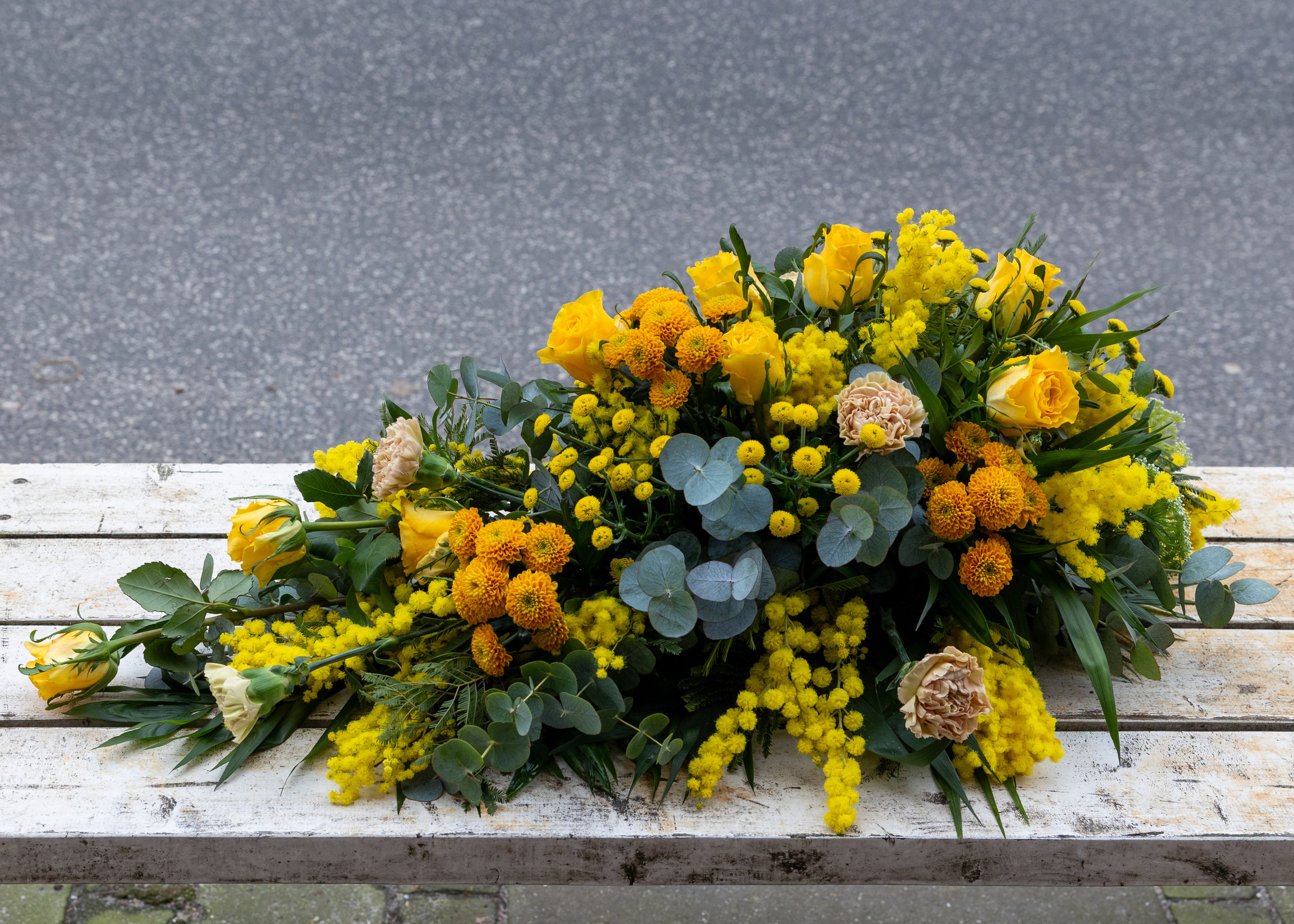 Gylden båredekorationSmuk båredekoration opbygget i oasis med højde og længde på blomsterstilkene. En klassisk udført båredekoration i sæsonens lyse og gyldne blomster. En elegant og smuk sidste hilsen. 