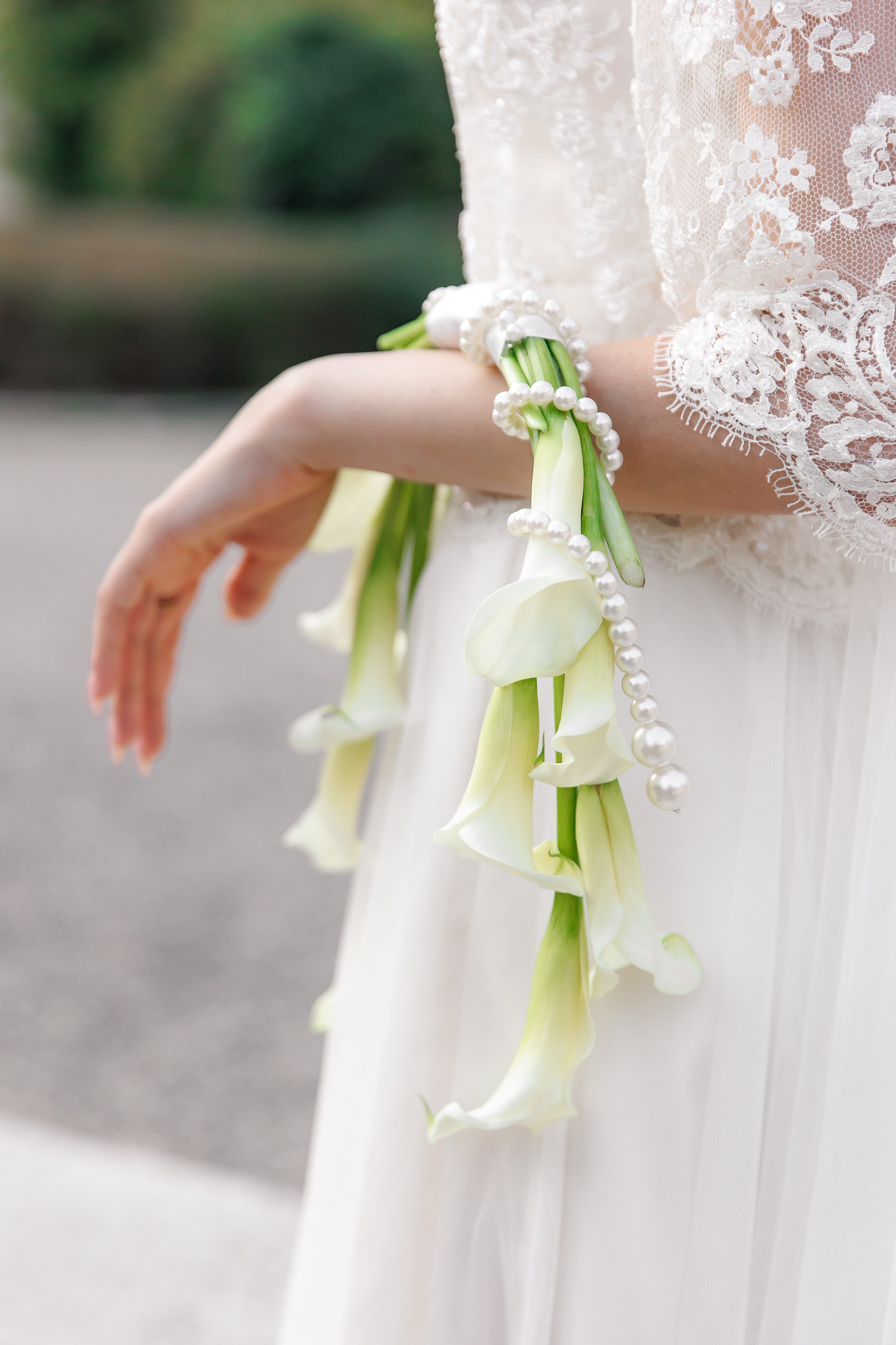 Bride is holding a bouquet made of callas