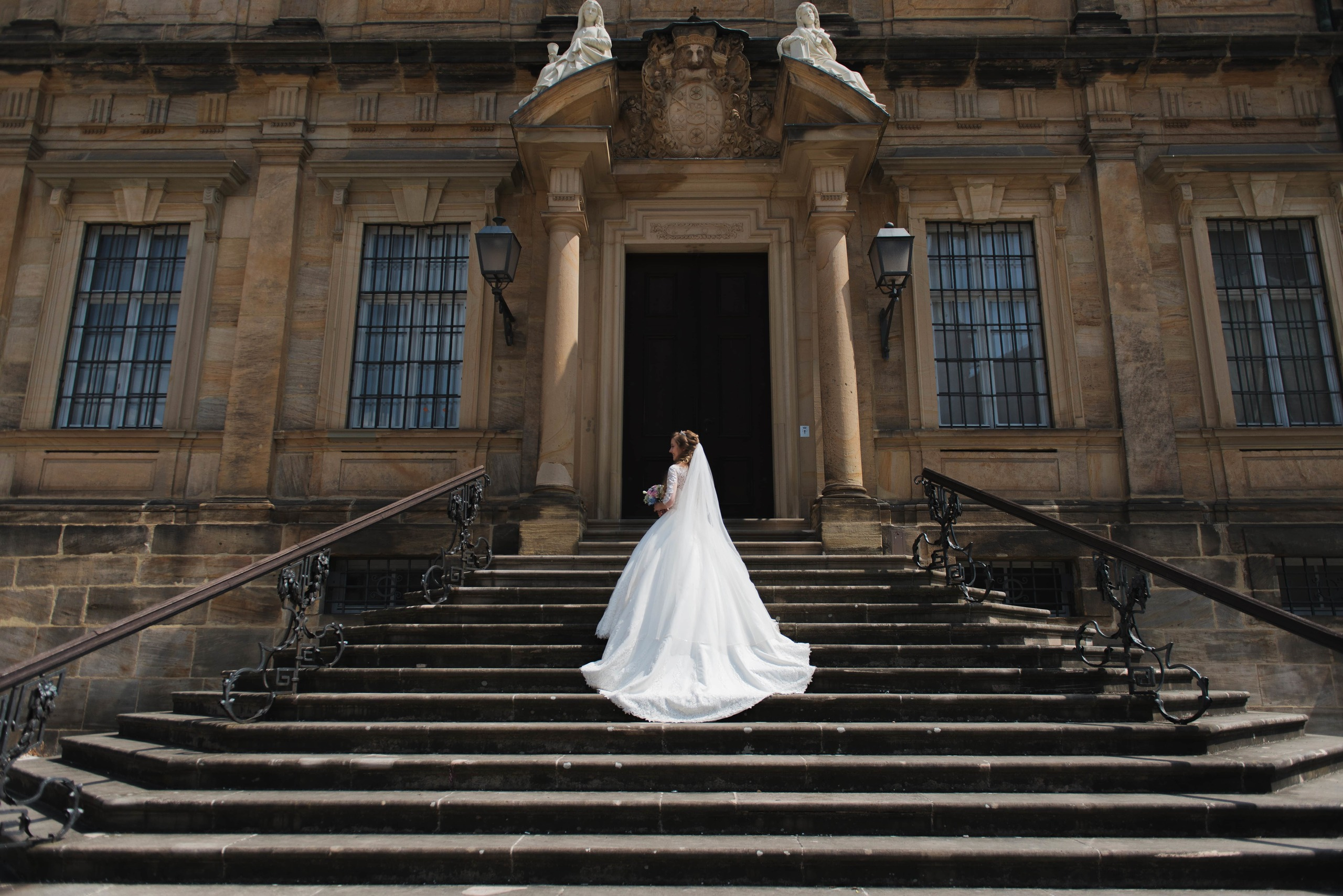 Braut steht auf der beeindruckenden historischen Treppe in Bamberg.
