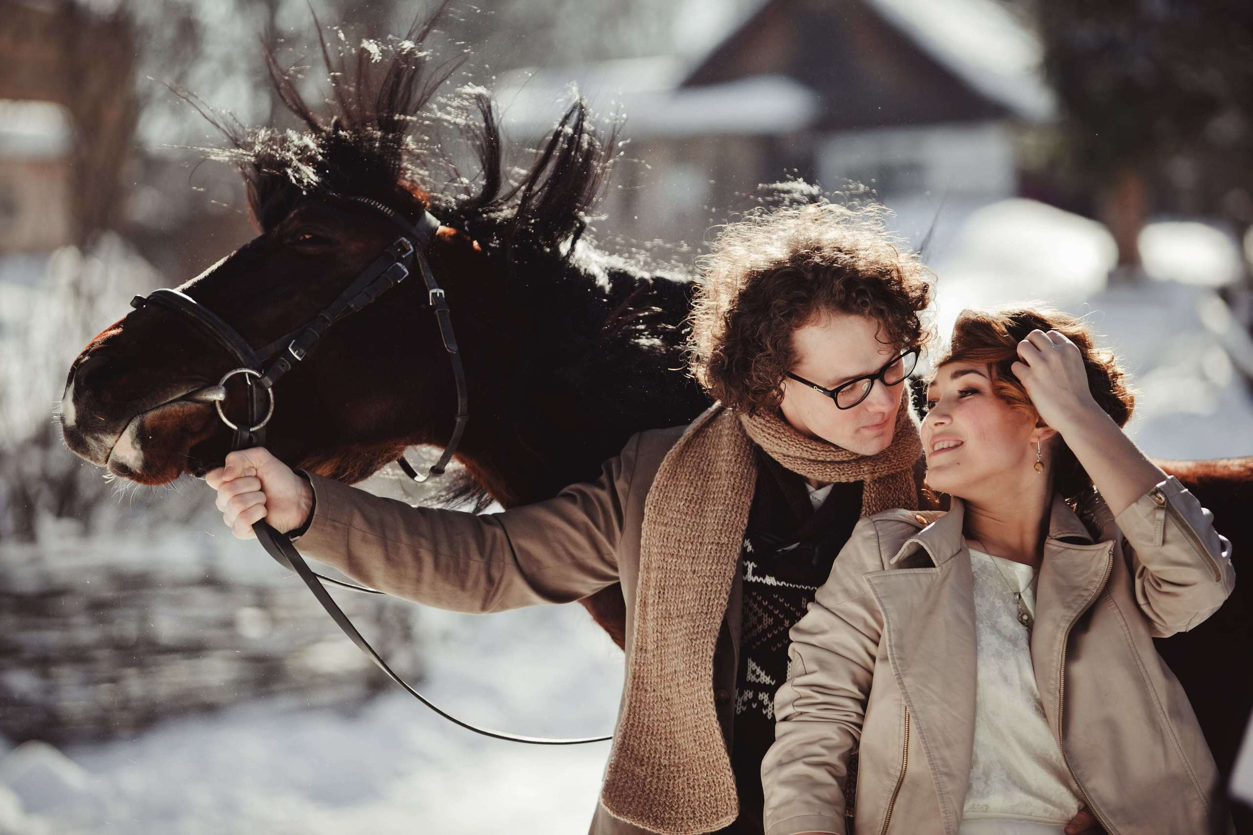 Bräutigam schaut die Braut an und hält mit der Hand die Zügel des Pferdes.