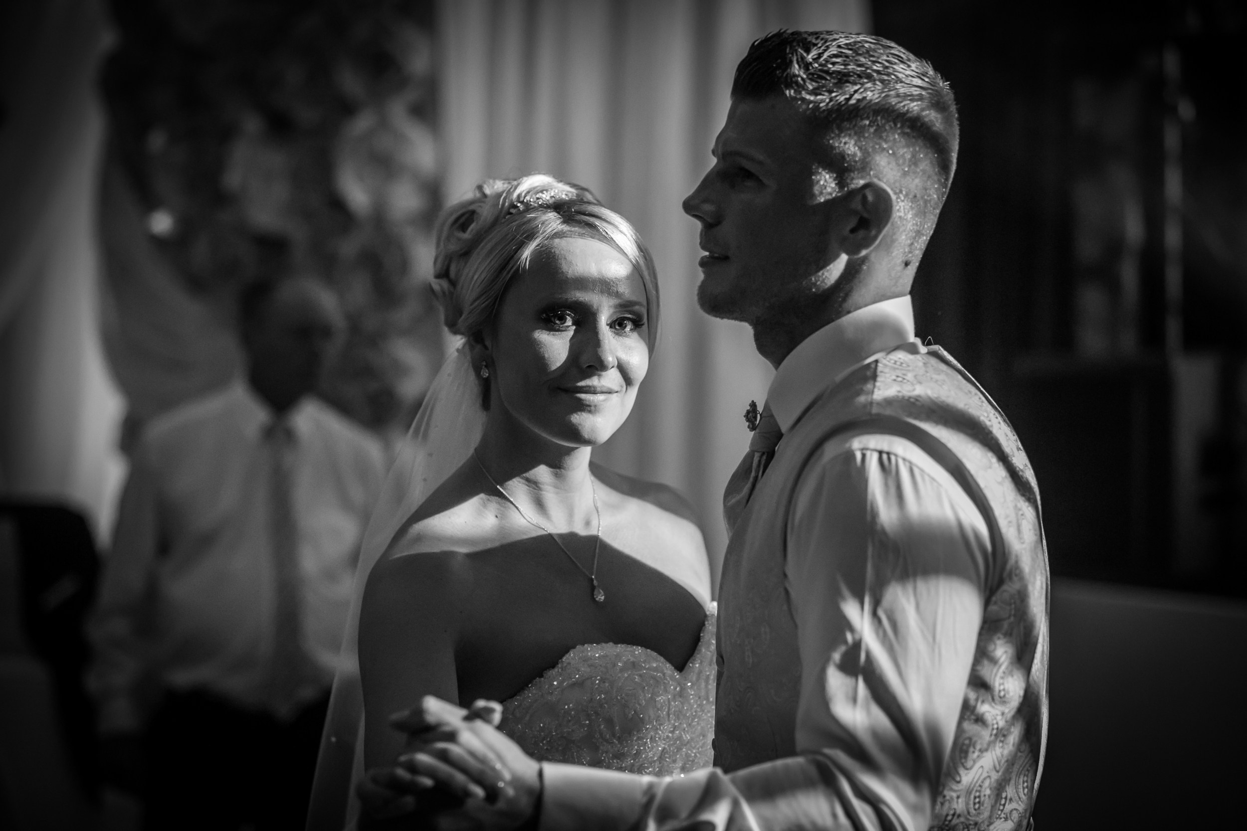 English:Black-and-white portrait of bride and groom gazing lovingly into each other’s eyes during the wedding ceremony. Bride in a strapless sparkling wedding dress with veil and delicate necklace, holding a bouquet, groom in a patterned vest and tie with boutonniere. Soft sunlight highlights their emotional connection, timeless and intimate moment. Photo by © Sergej NevelskijРусский:Черно-белый портрет жениха и невесты, нежно смотрящих друг другу в глаза во время церемонии. Невеста в сверкающем платье без бретелей с фатой и тонким ожерельем, с букетом в руках, жених в узорчатом жилете и галстуке с бутоньеркой. Мягкий солнечный свет подчёркивает их эмоции — трогательный и вечный момент. Фото © Sergej NevelskijDeutsch:Schwarz-Weiß-Porträt von Braut und Bräutigam, die sich während der Trauung zärtlich in die Augen schauen. Braut in einem trägerlosen, glitzernden Brautkleid mit Schleier und feiner Kette, Brautstrauß in den Händen, Bräutigam in gemusterter Weste und Krawatte mit Ansteckblume. Weiches Sonnenlicht betont die tiefe emotionale Verbindung – ein zeitlos intimer Augenblick. Foto © Sergej Nevelskij