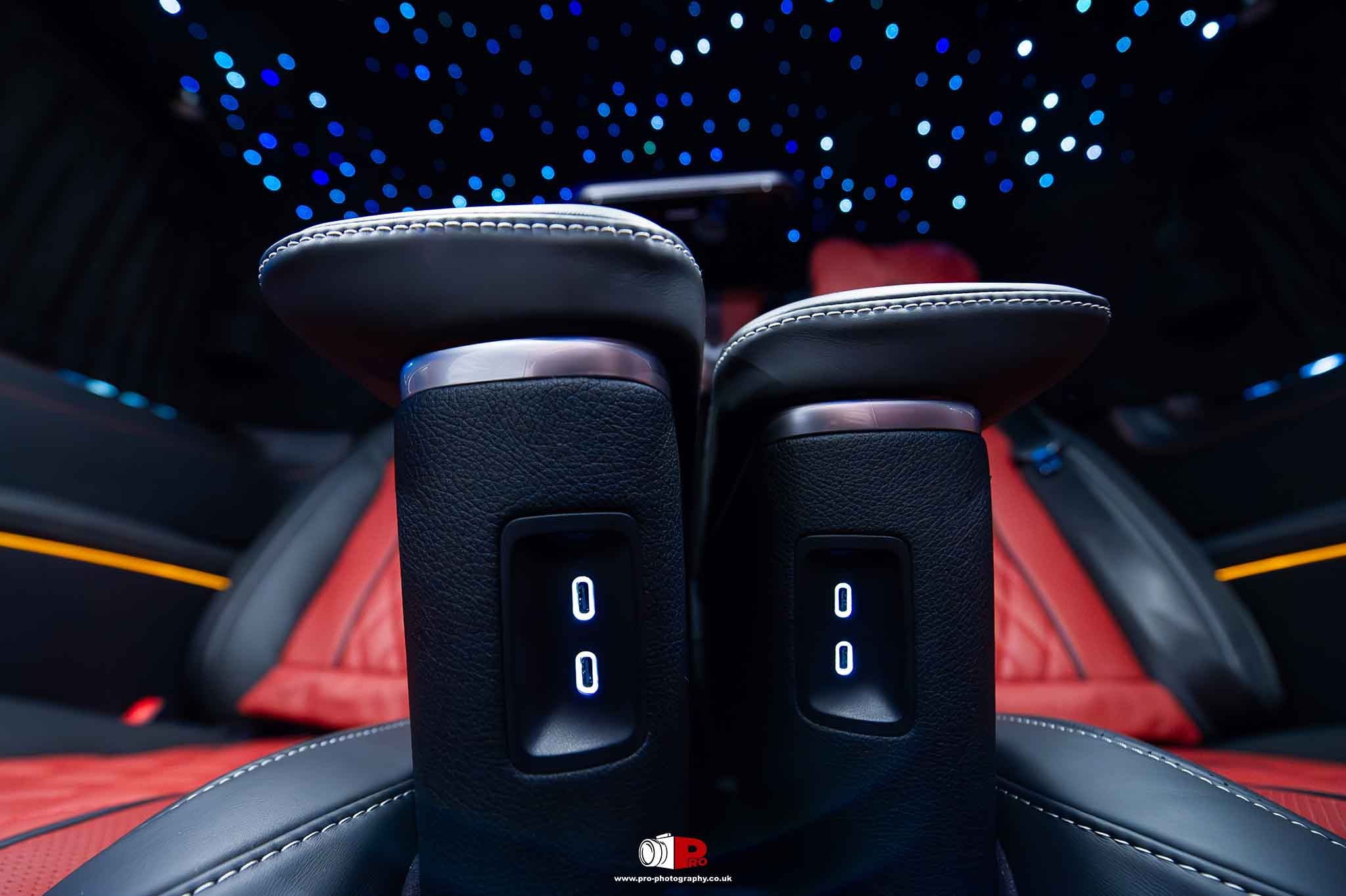 Elegant car interior featuring red leather seats and ambient star ceiling lighting.