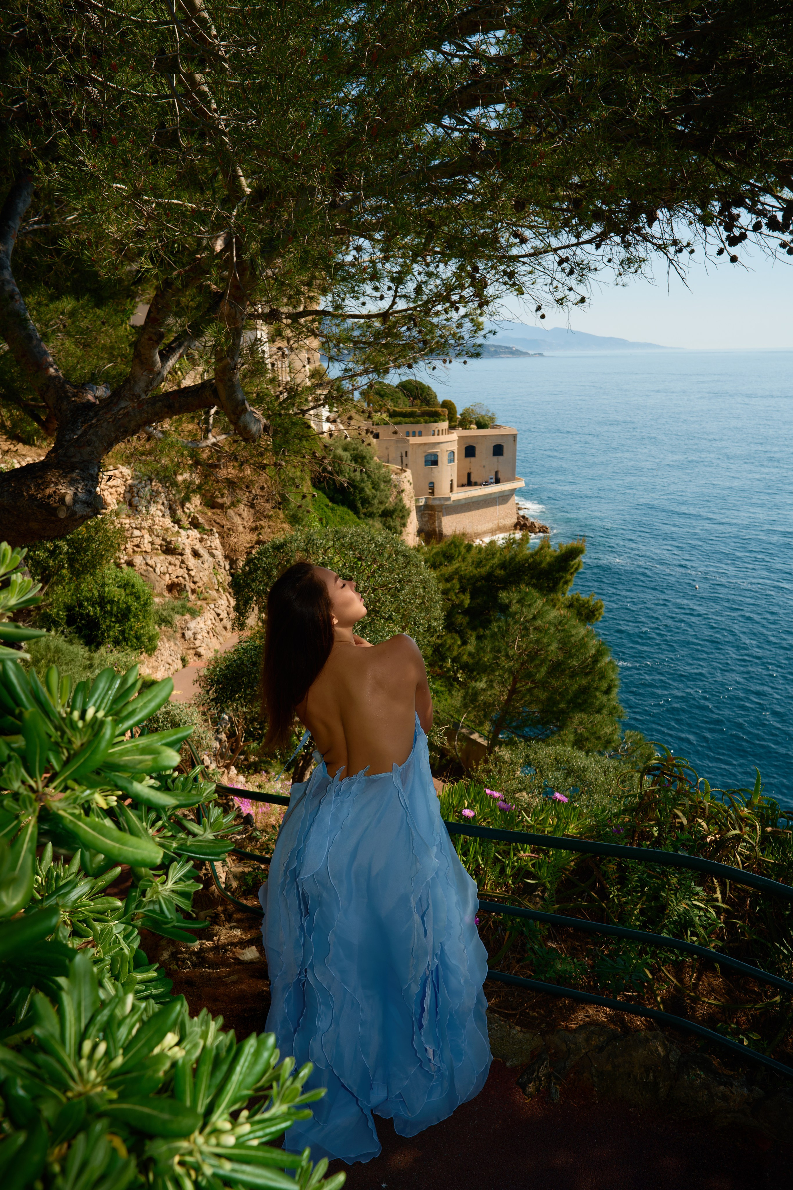 Woman in elegant gown sitting on terrace with panoramic Monaco ocean view