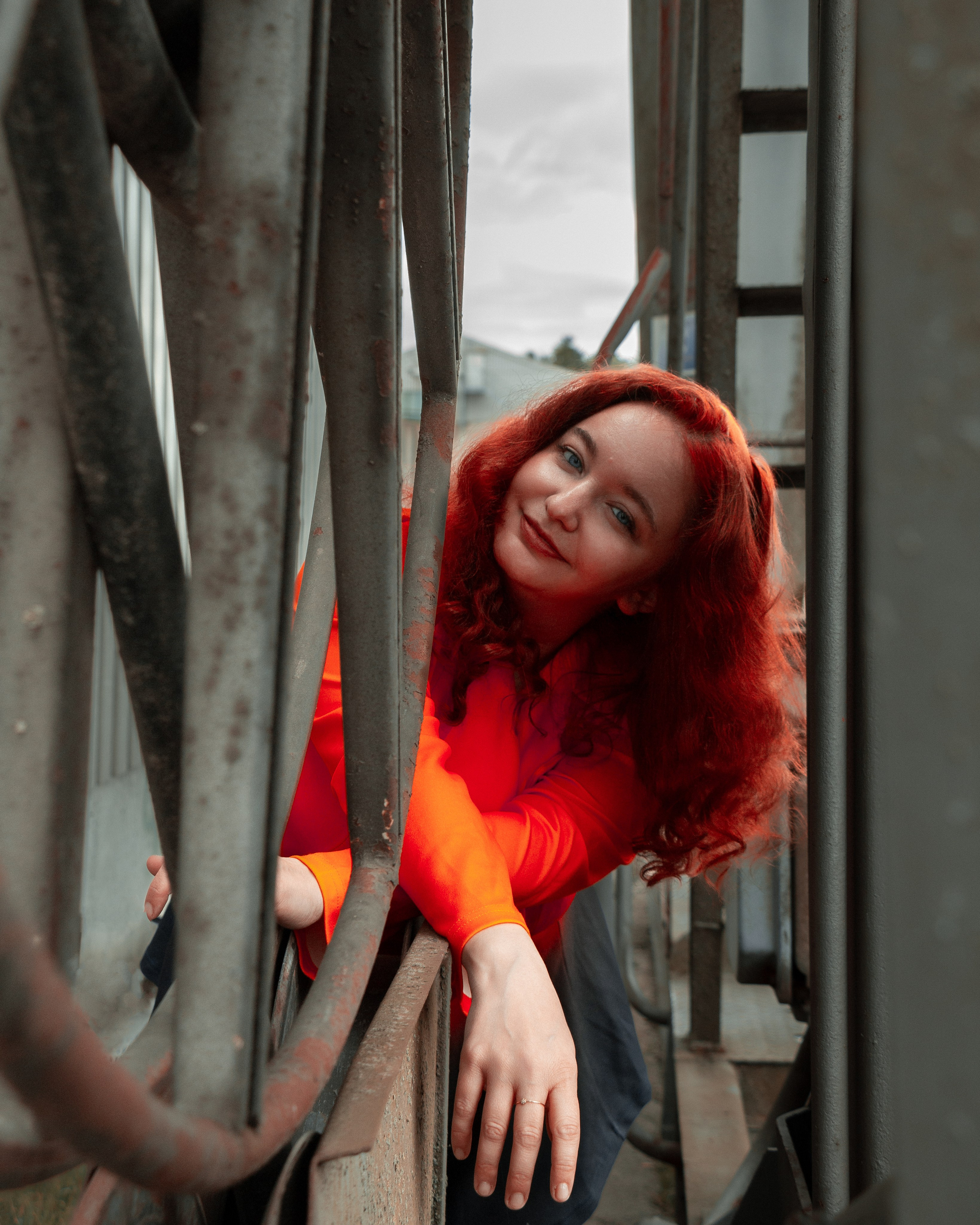 Modisches Straßenportrait mit Ksenia in rotem Kleid und leuchtenden Haaren