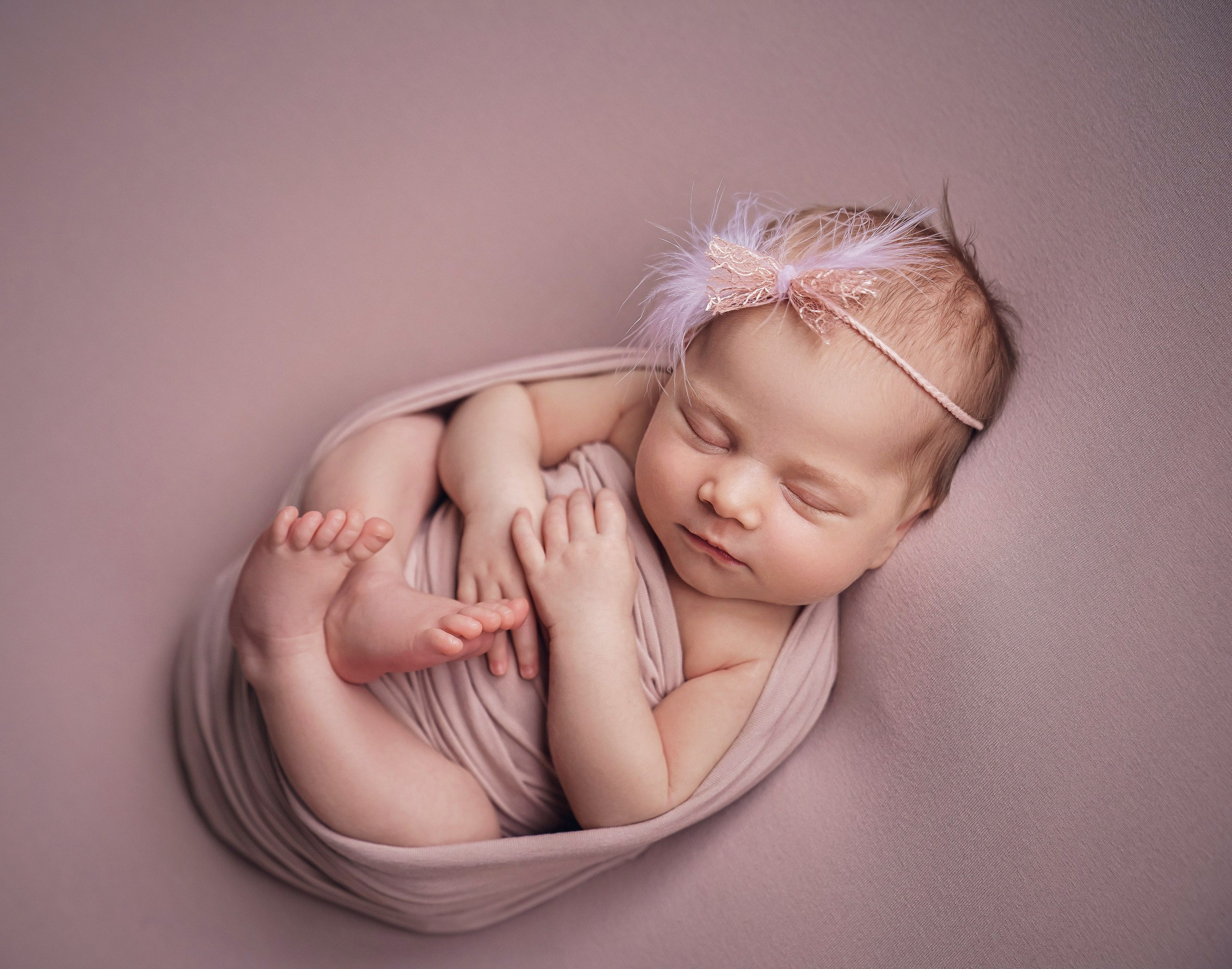 Newborn baby girl sleeping on back in dreamy pose