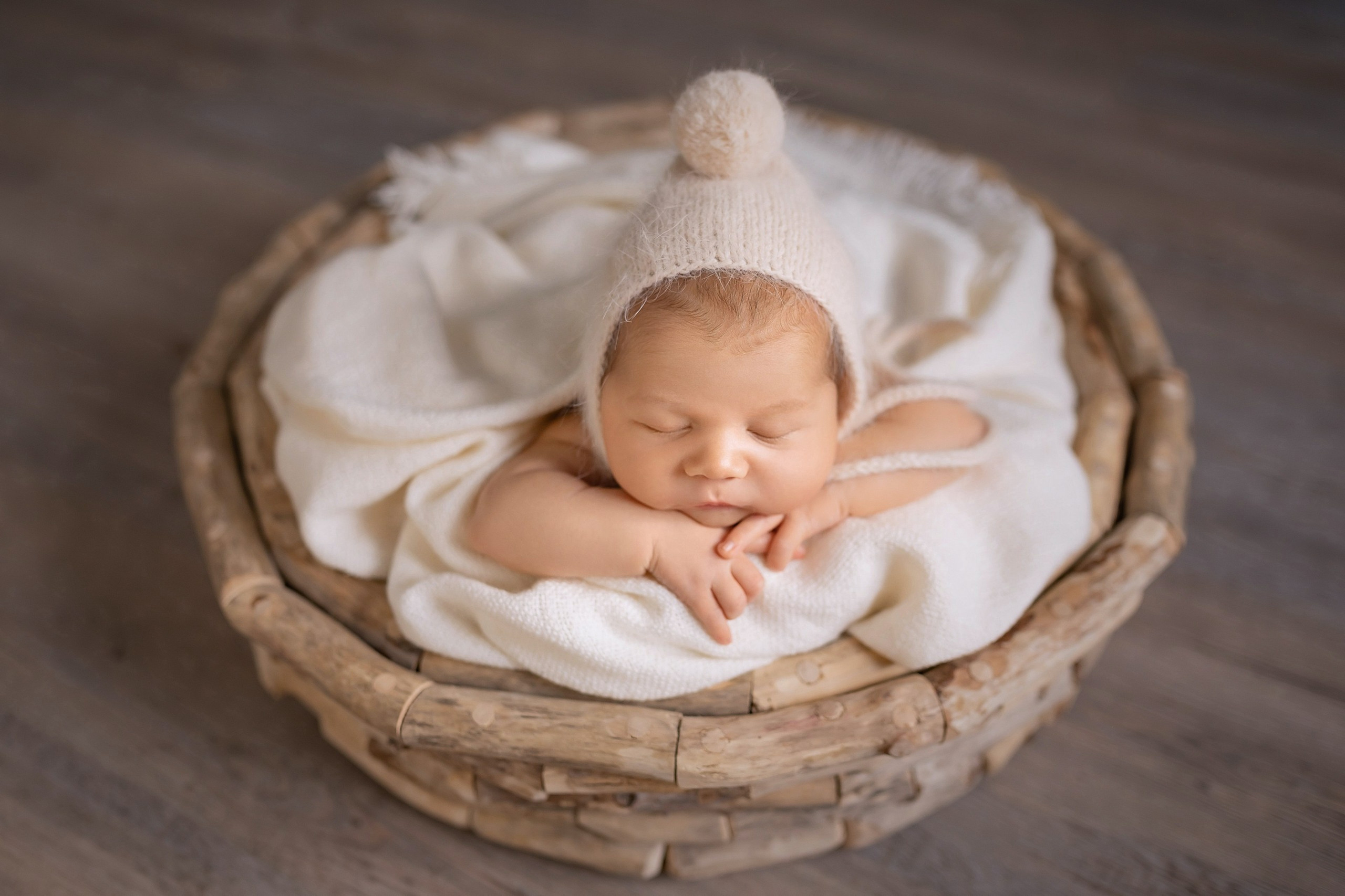Newborn baby girl sleeping peacefully in a round woven basket