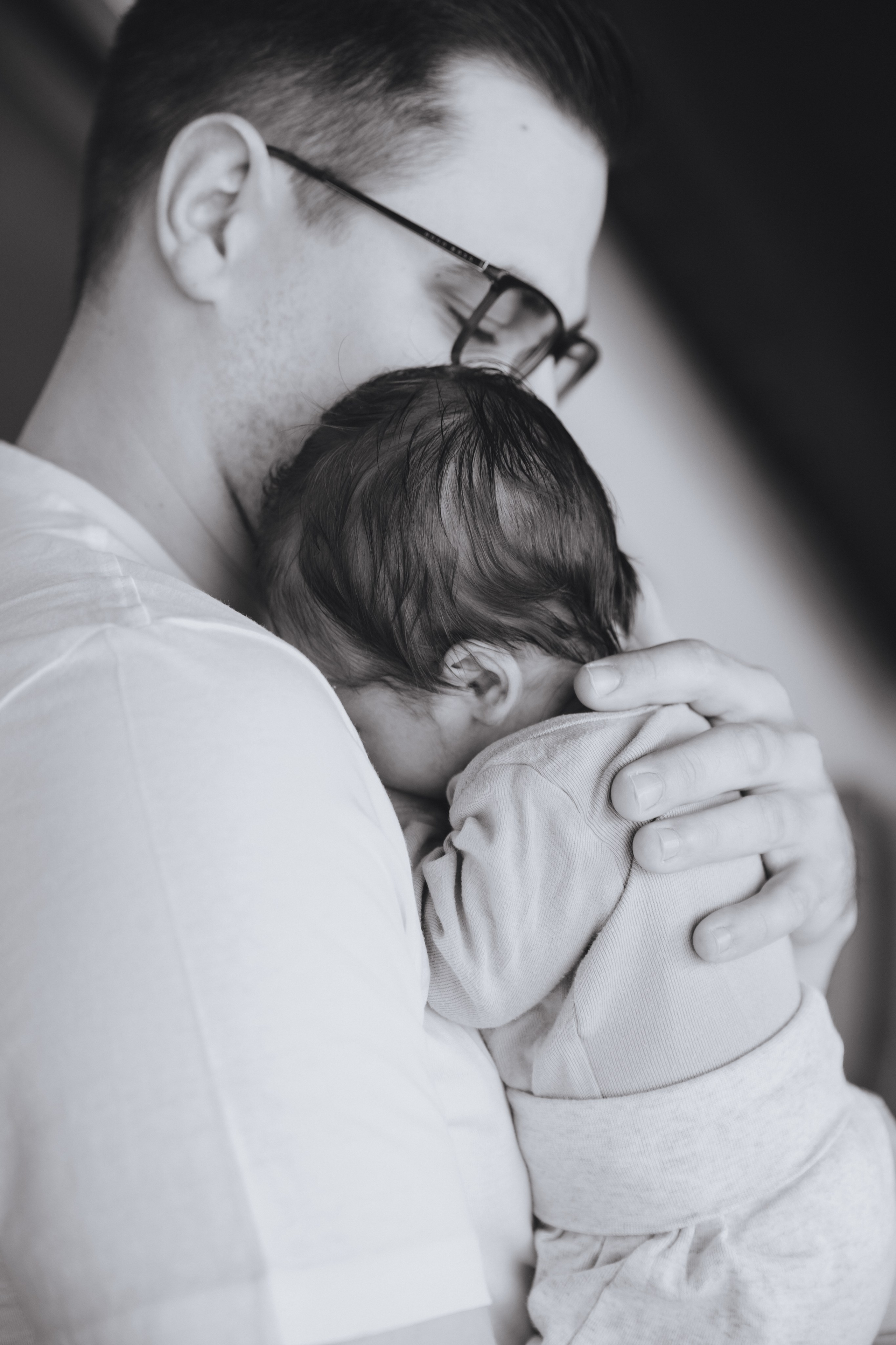 Papa hält sein neugeborenes Baby liebevoll in den Armen während des Neugeborenen-Shootings.