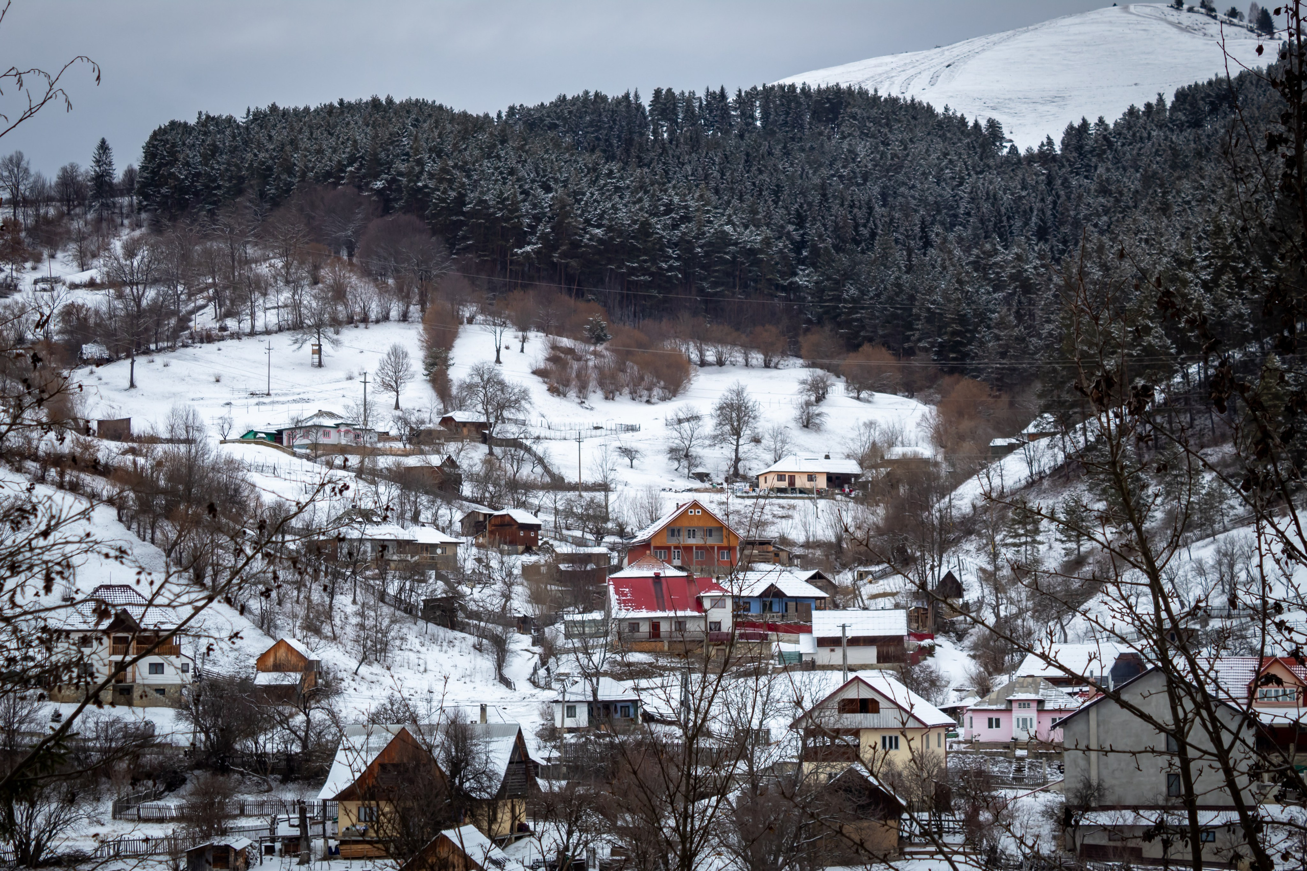 Aerial view of a snow-covered village nestled between forested hills.