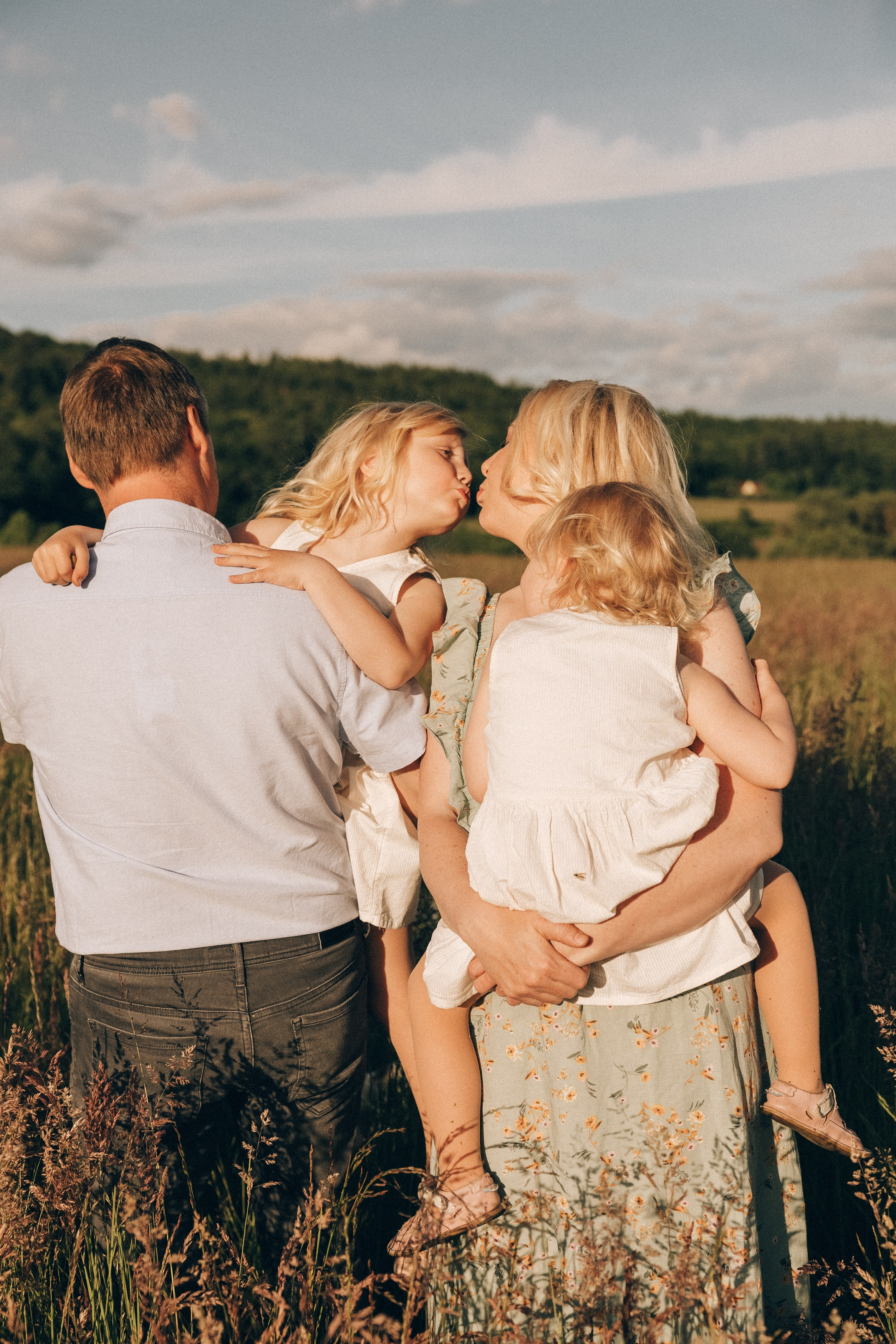 Family photoshoot in a daisy meadow at golden hour — natural light, warm tones, candid moments between a mother and her daughters. Lifestyle and Family Photographer in Pisek Oxana Telupilova