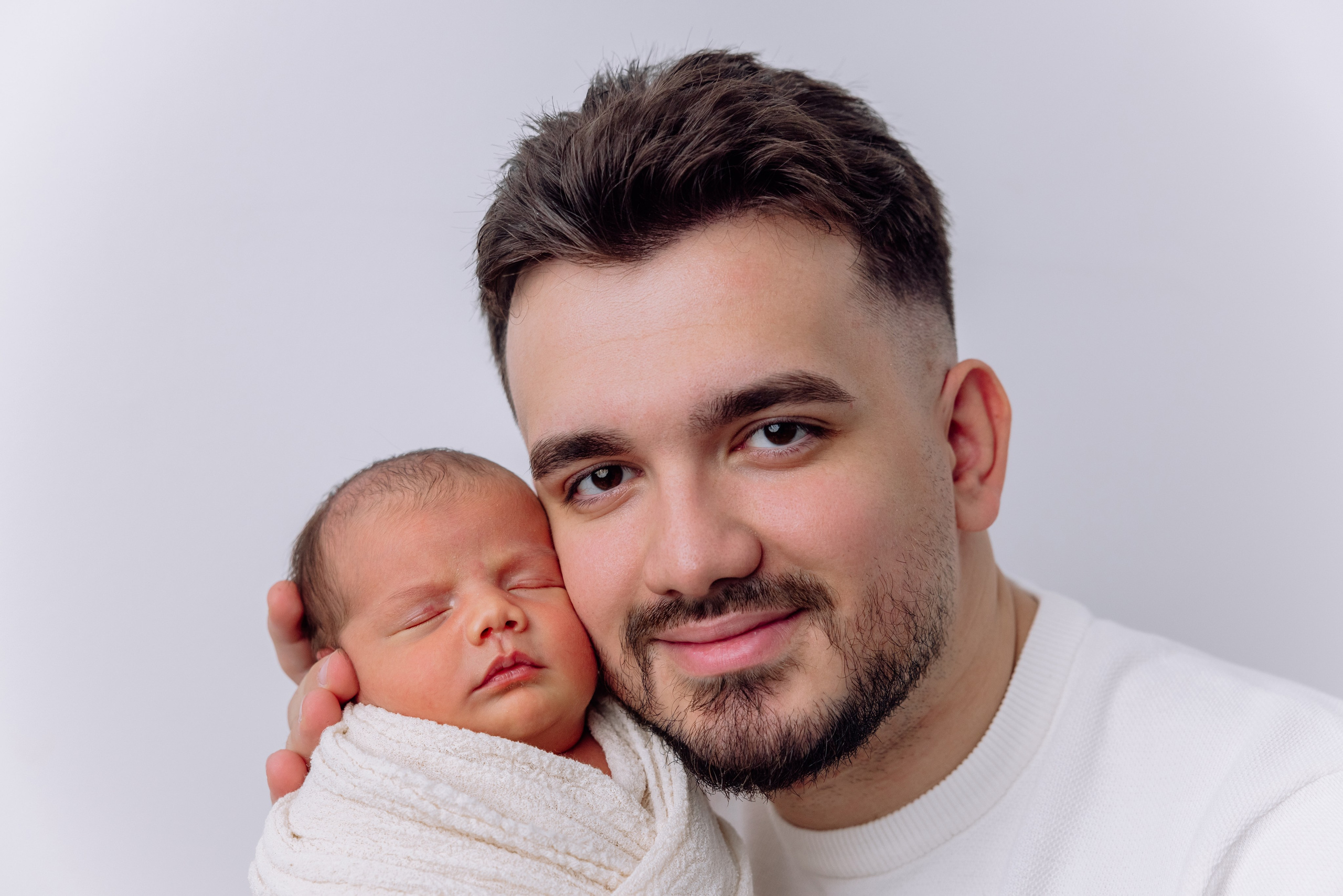 Vater und Neugeborenes eng aneinander – emotionales Familienshooting München