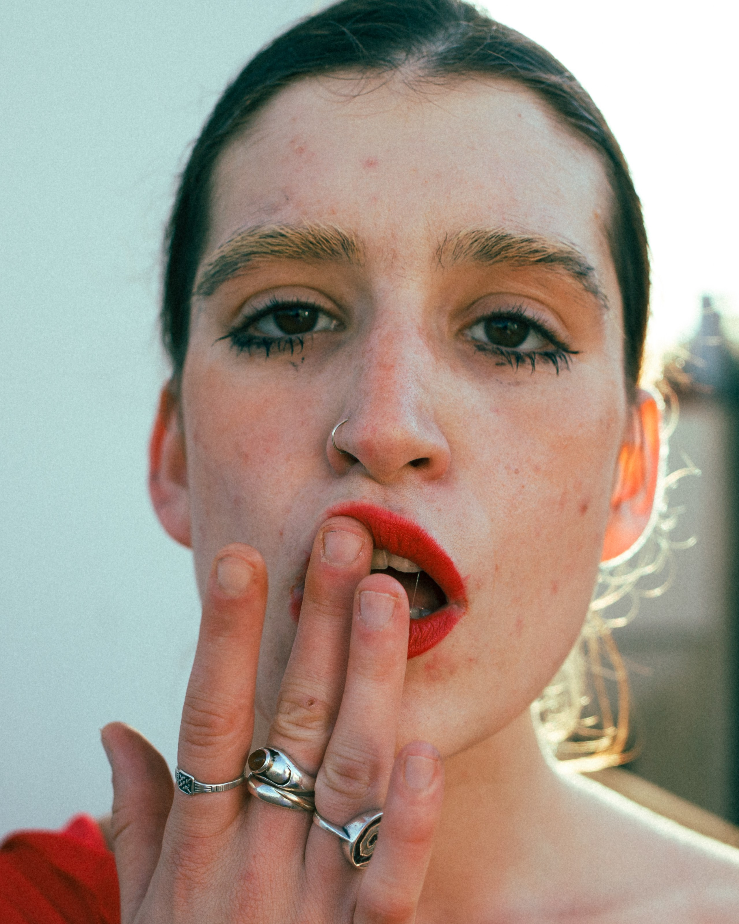 Close-up of a woman with red lipstick, touching her lips