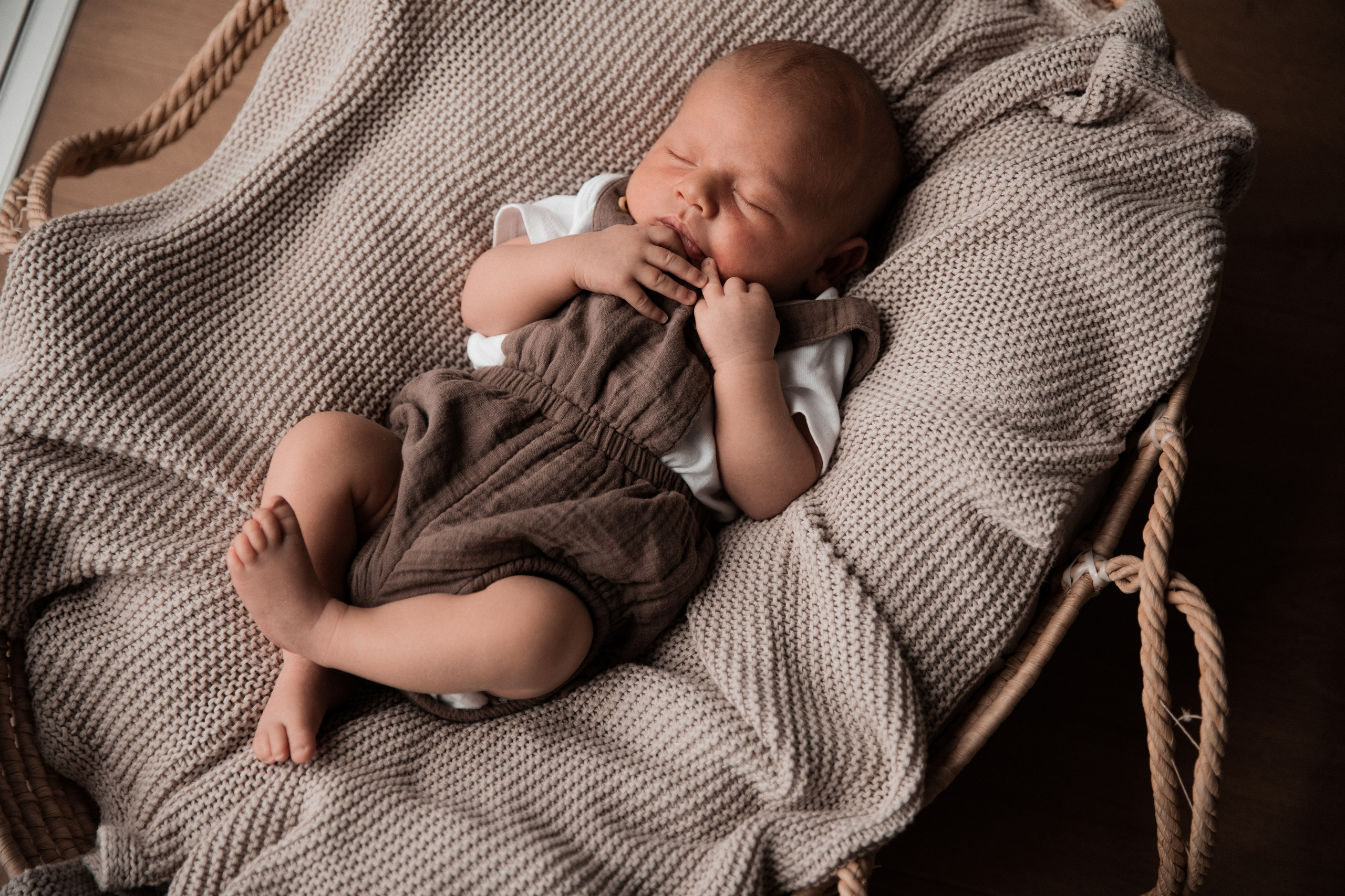 Baby liegt schlafend im Korb während des Fotoshootings.