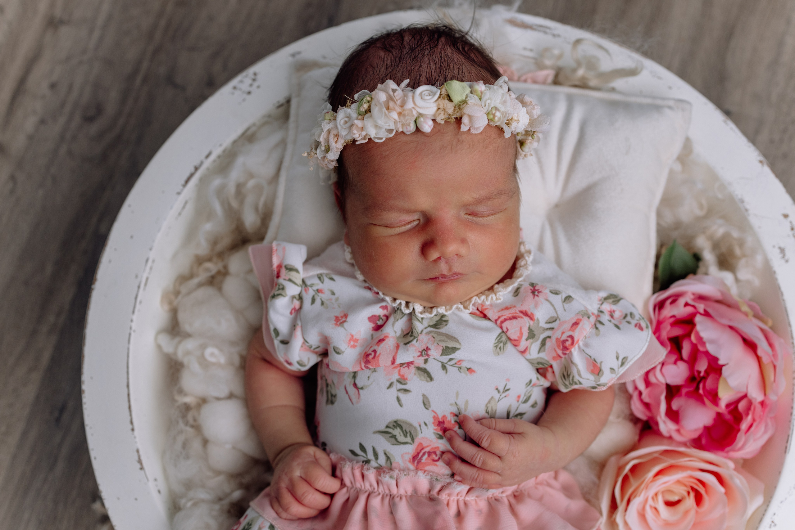 Baby liegt in Korb, umgeben von Blumen – entspannte Fotografie zuhause.