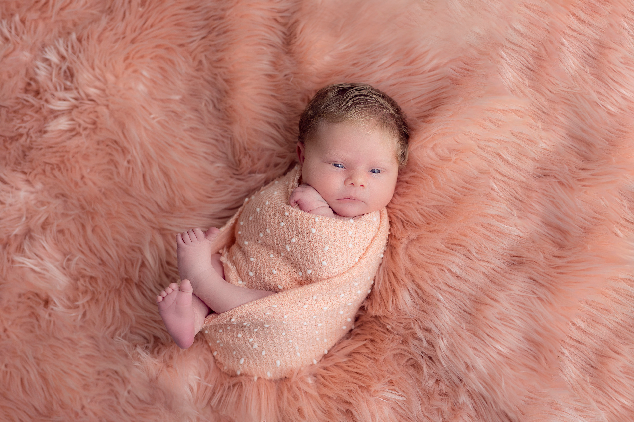 Een klein meisje ligt rustig te slapen in een mandje met dekentjes.