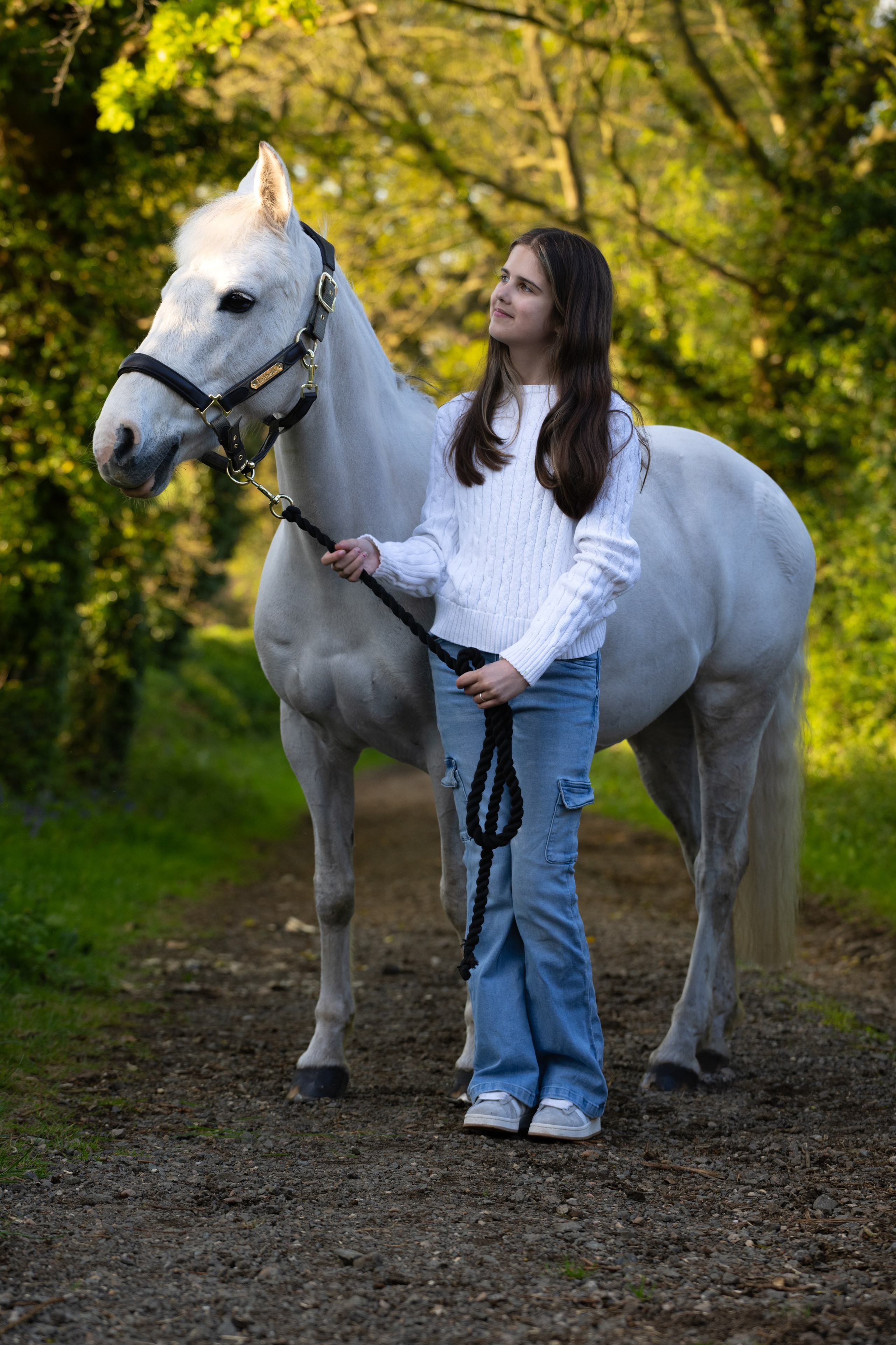 Happy girl holding reins of her pony during golden light portrait session