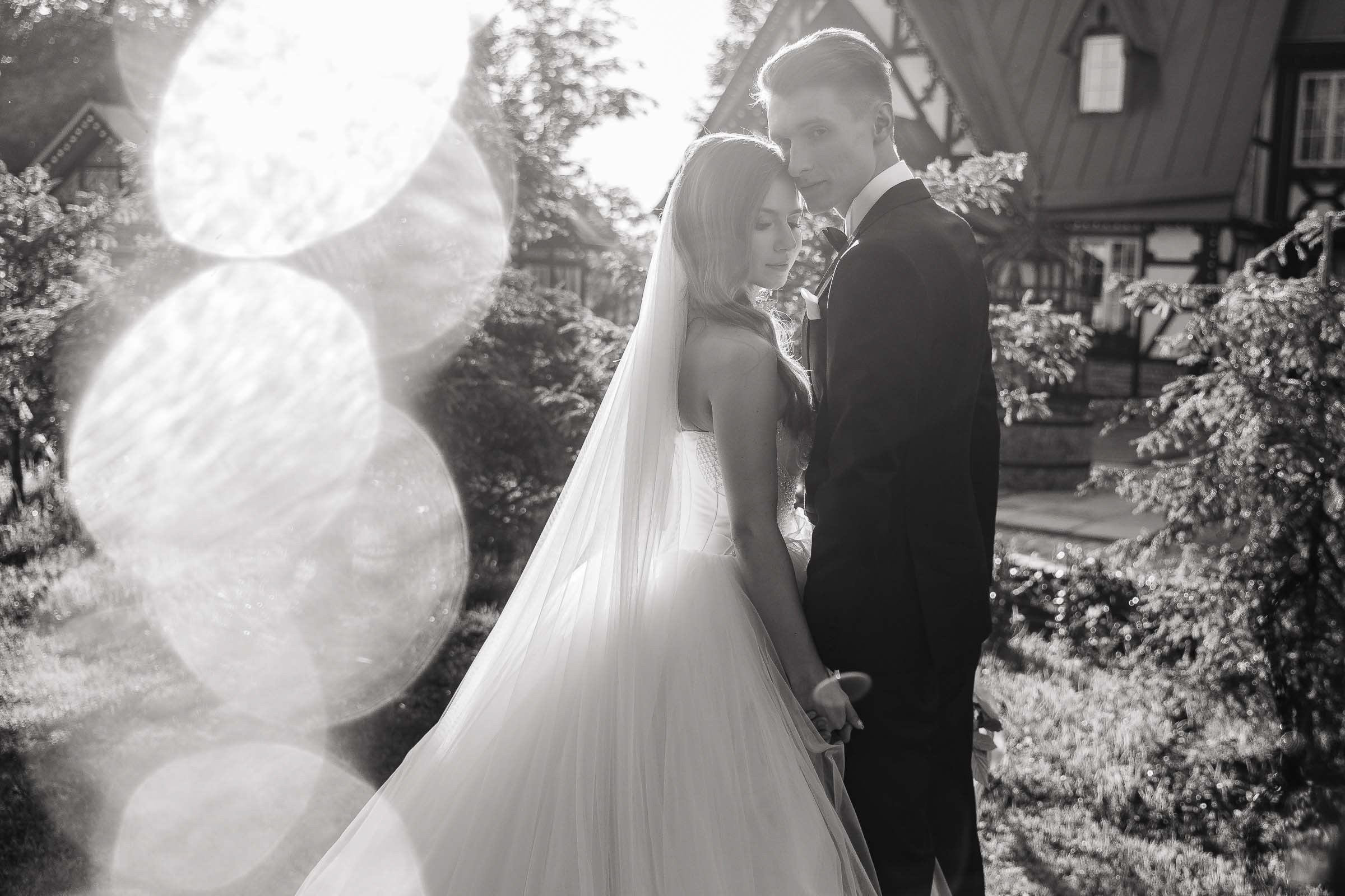 Bride and groom walk in gardens with grand house, by Tanya Bodgan, Bude, Cornwall wedding photographer.