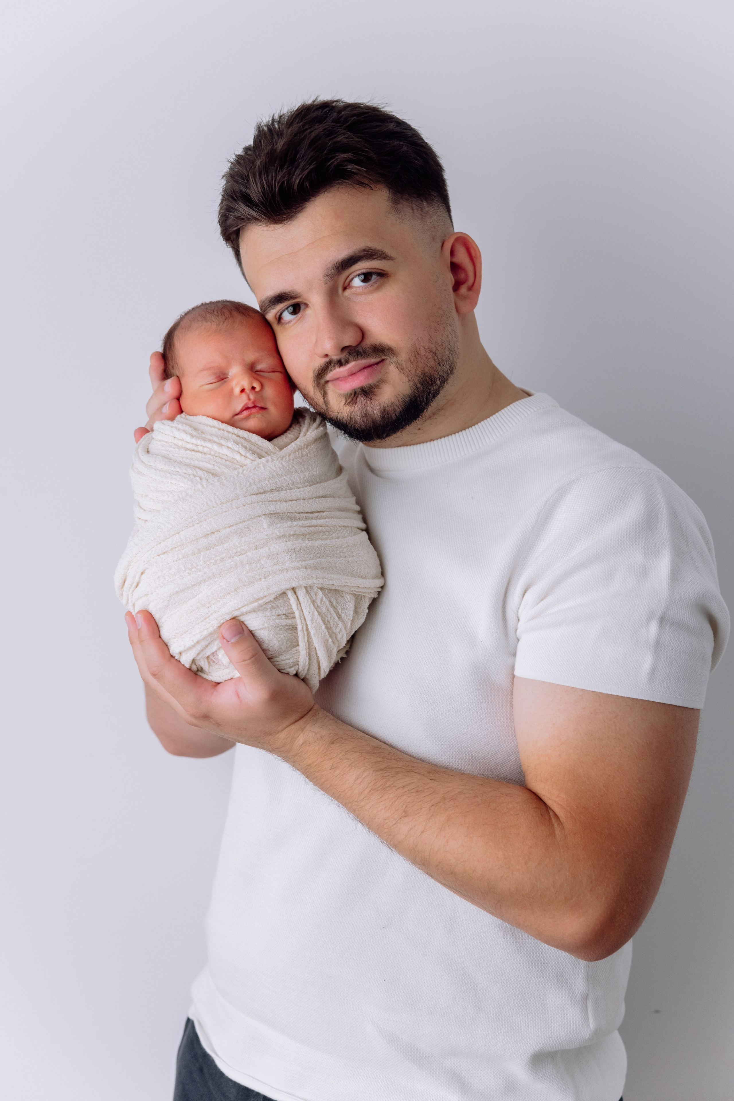 Vater hält den Säugling sanft auf der Brust – zärtlicher Moment zuhause.