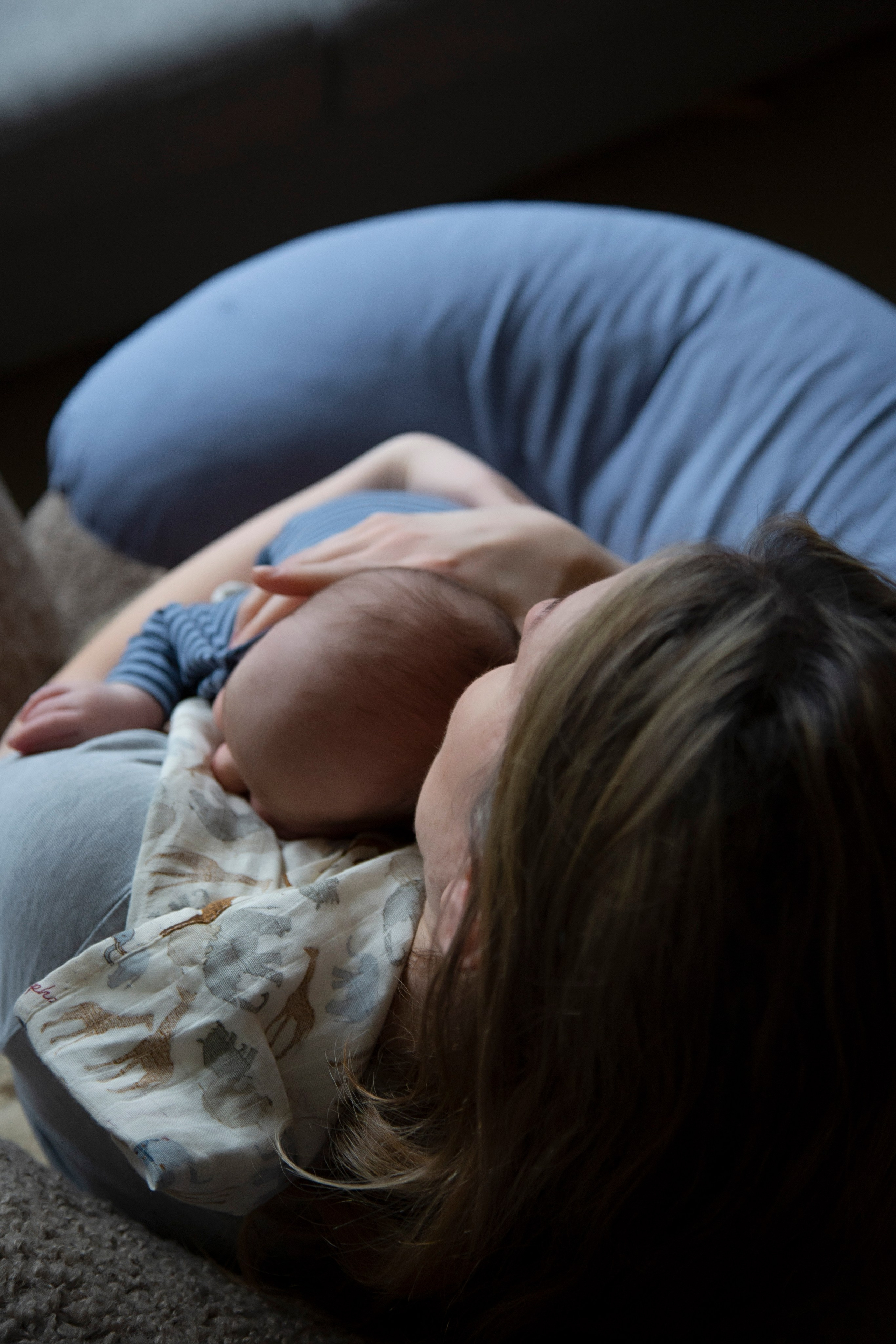 Overhead view of mother sitting and cradling newborn baby in her arms, capturing a tender moment of maternal love