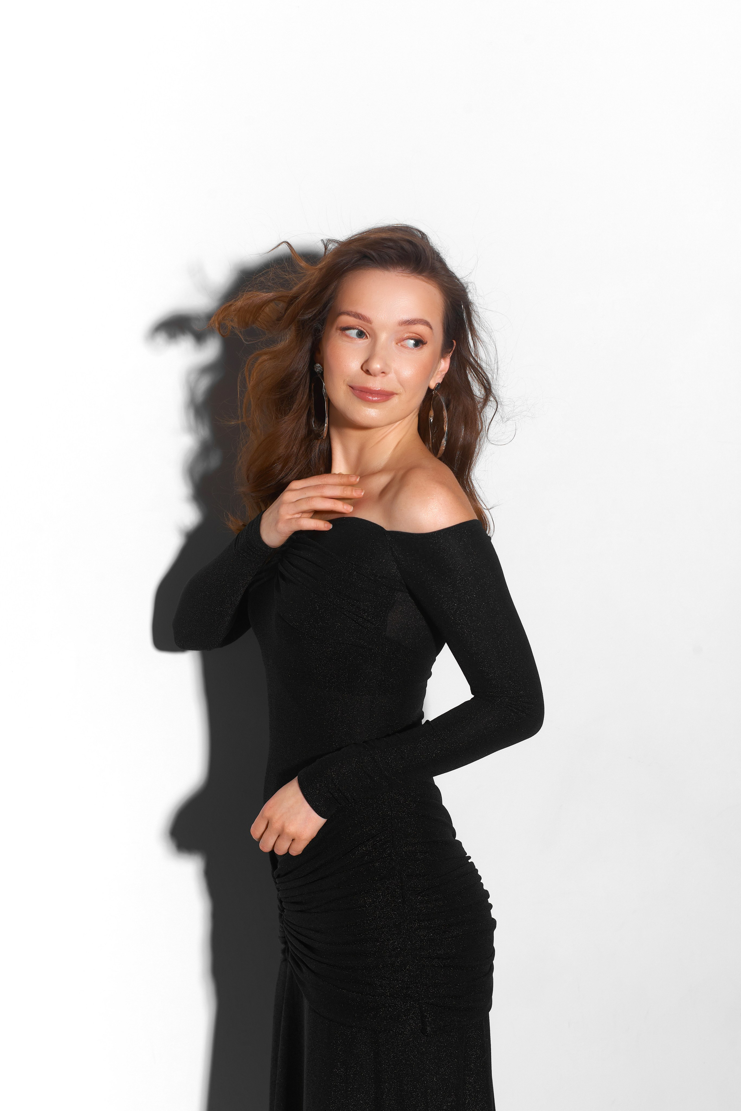 Minimalistyczna sesja portretowa – kobieta w czarnej sukience na białym tle, delikatne światło i naturalna ekspresja