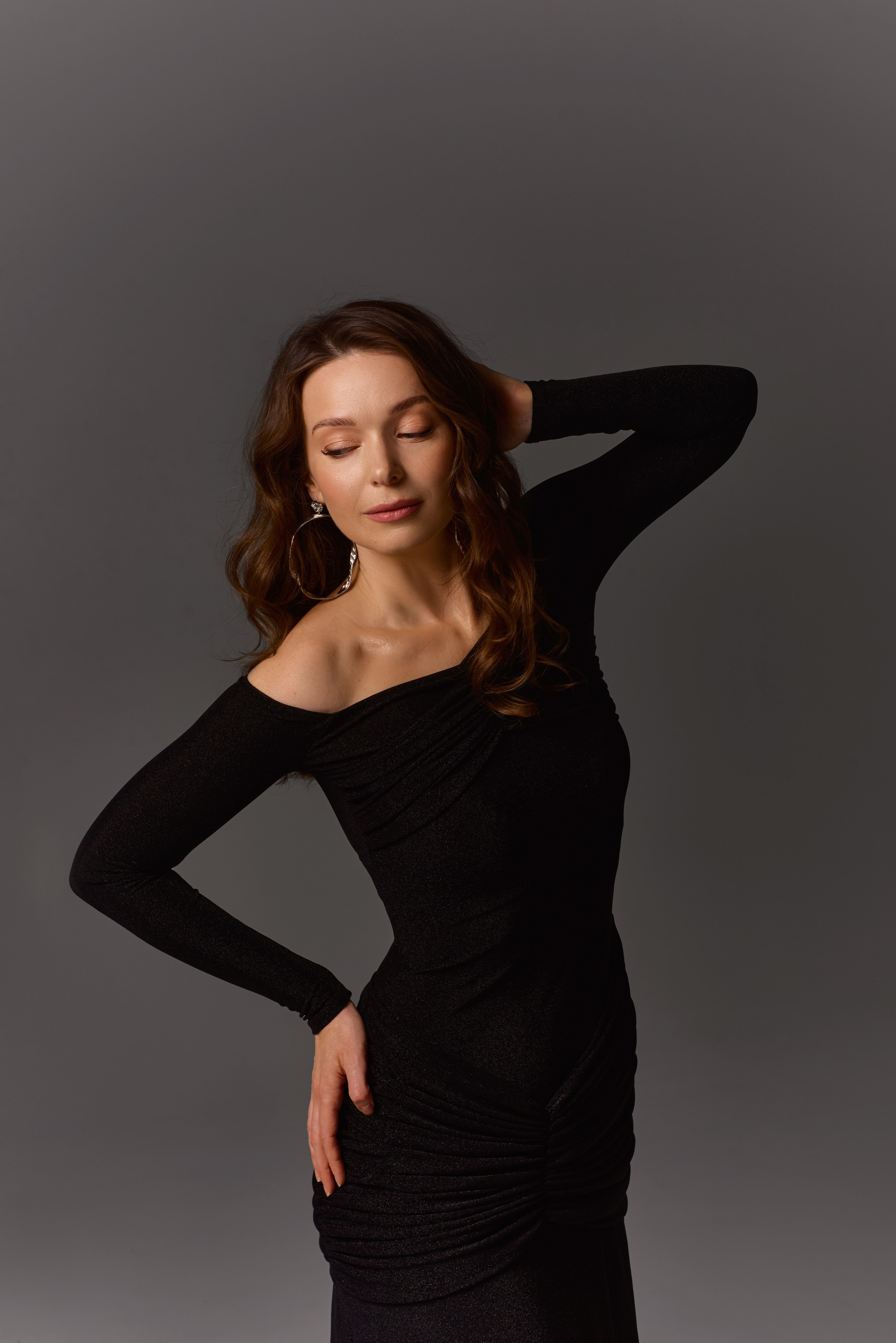 Stylowa sesja portretowa – kobieta w czarnej dopasowanej sukience na szarym tle, elegancja i kobiecość