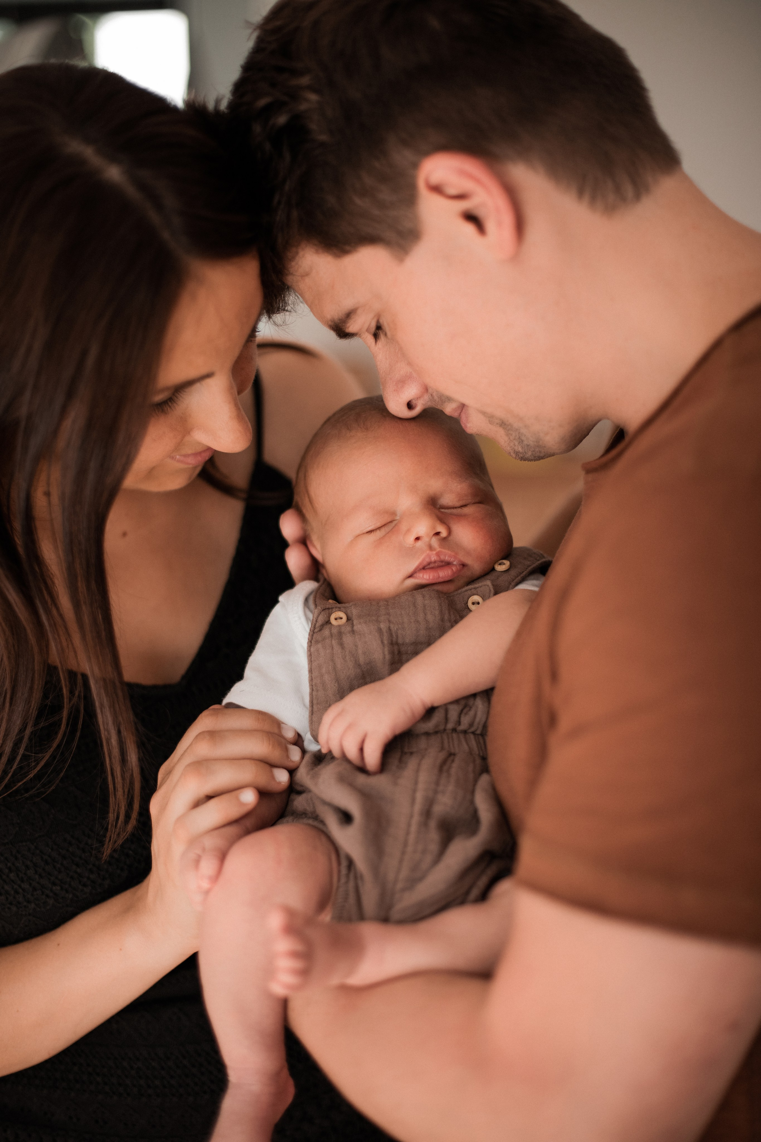 Mama und Papa umarmen ihren kleinen Sohn liebevoll am Fenster.