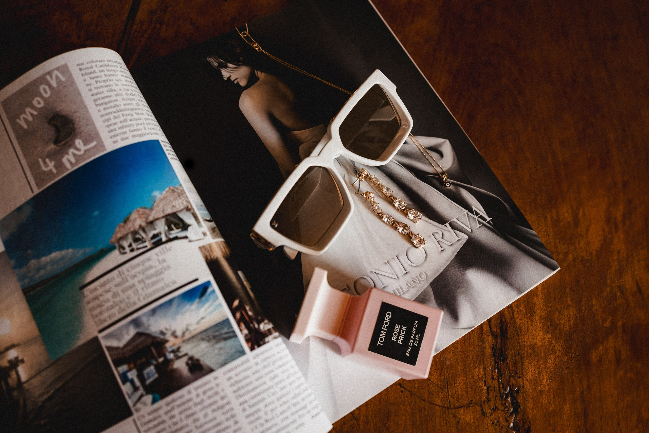 Flat lay de acessórios de noiva: óculos brancos, brincos de pérola e revista de inspiração wedding.