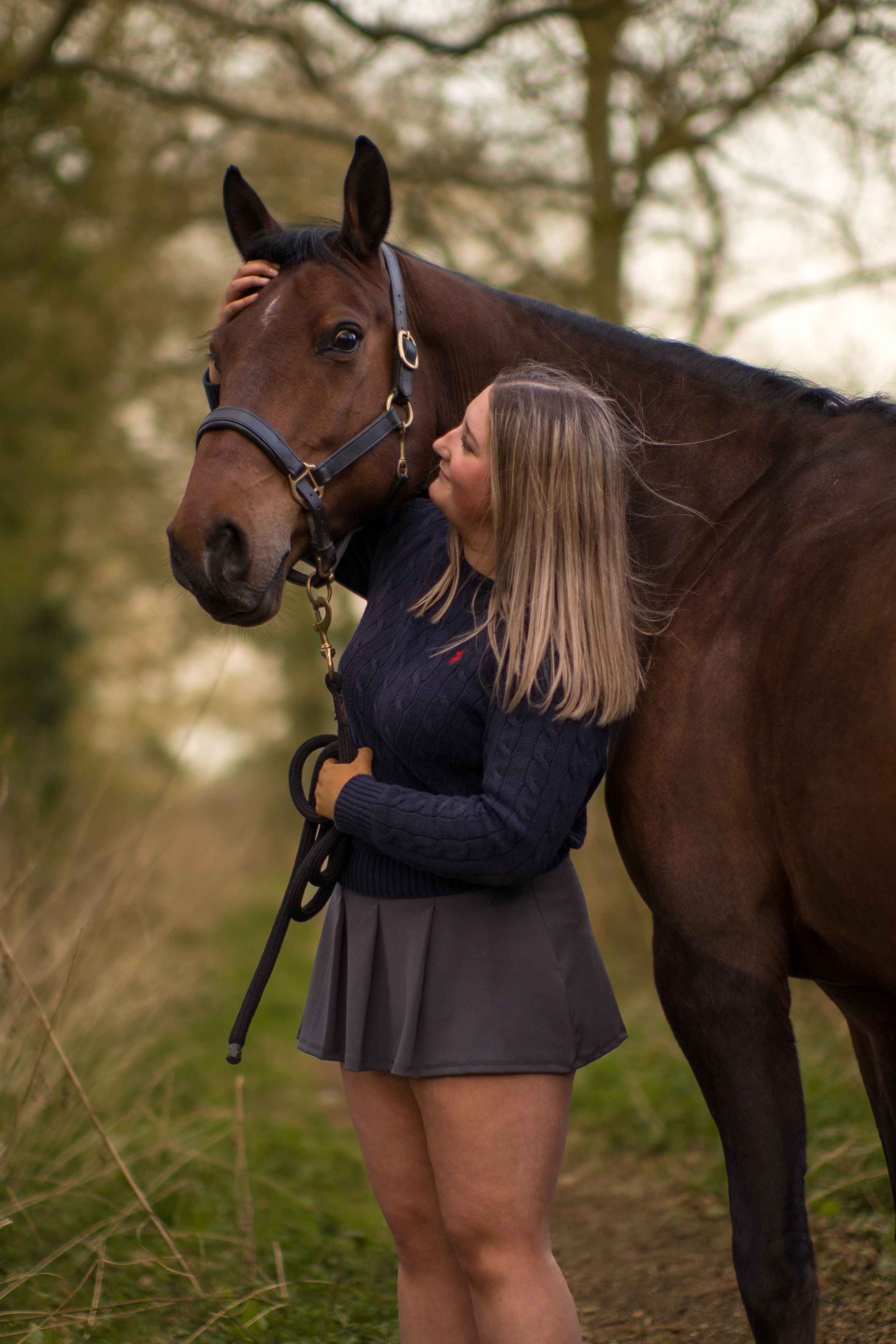 Young girl walking with a brown pony at sunset in Leicestershire countryside
