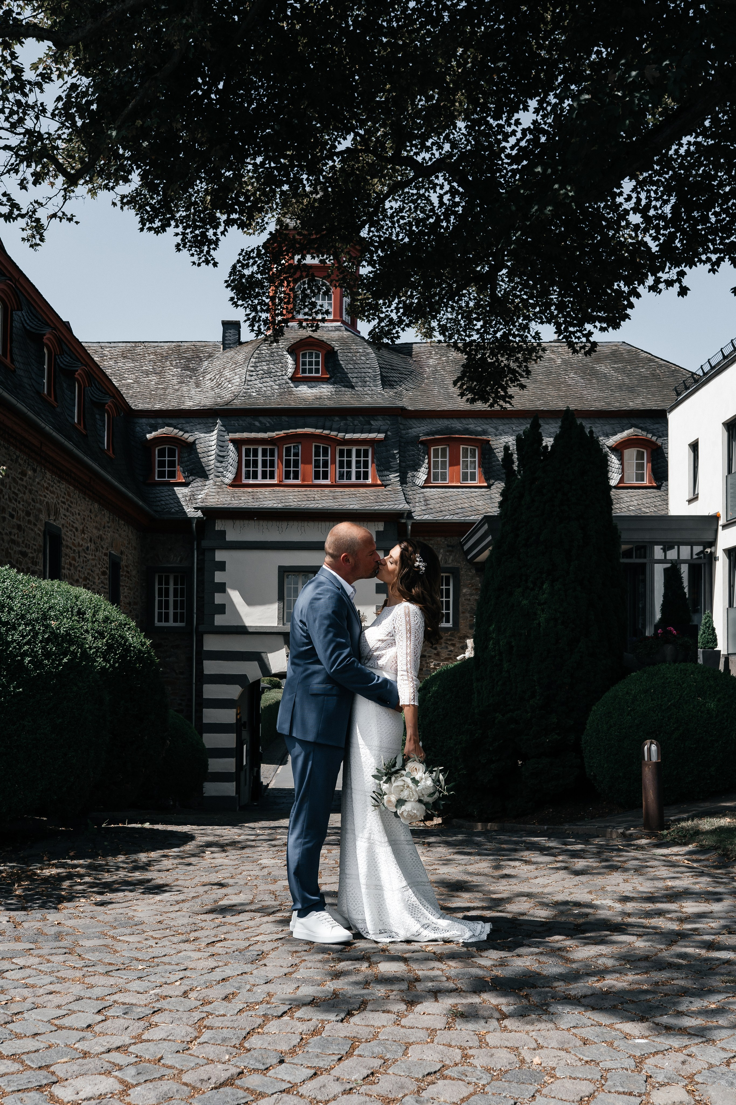 Brautpaar in liebevoller Umarmung vor einem historischen Schloss, das die Hochzeit perfekt in Szene setzt