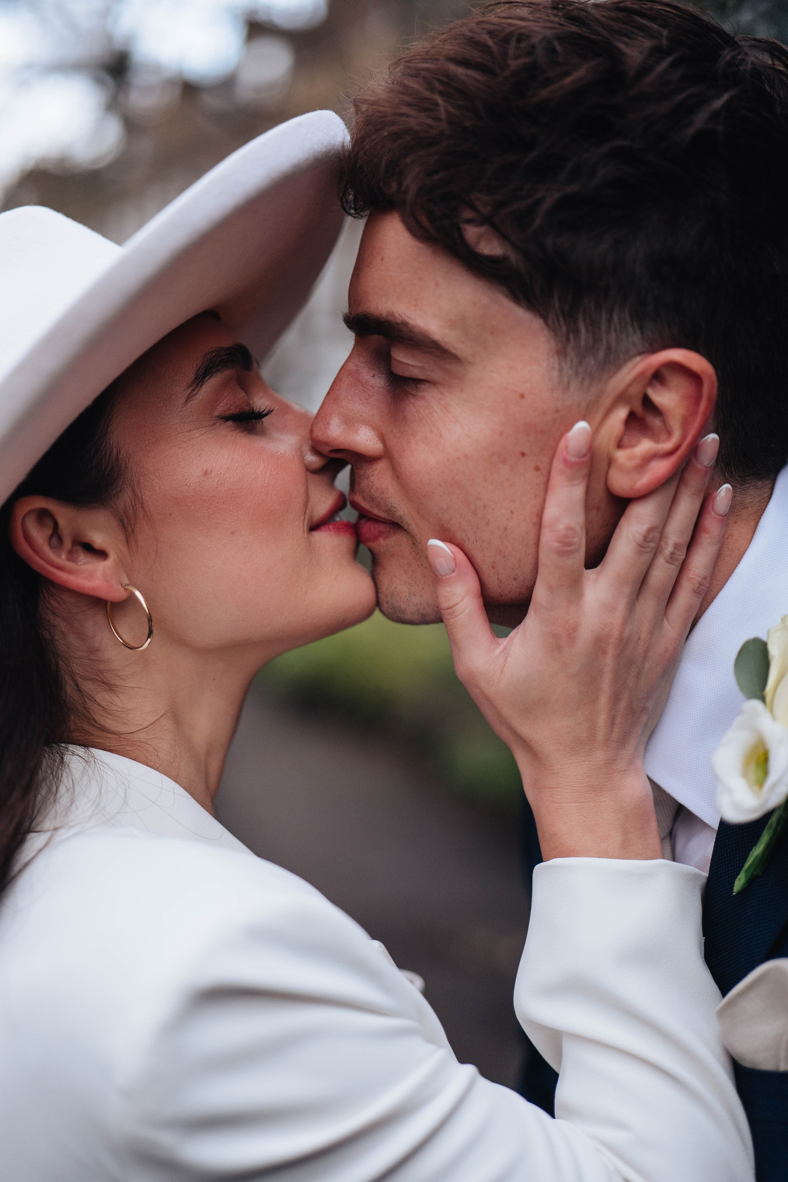 Stylish wedding in Islington, white women costume and white hat, kissing closeup